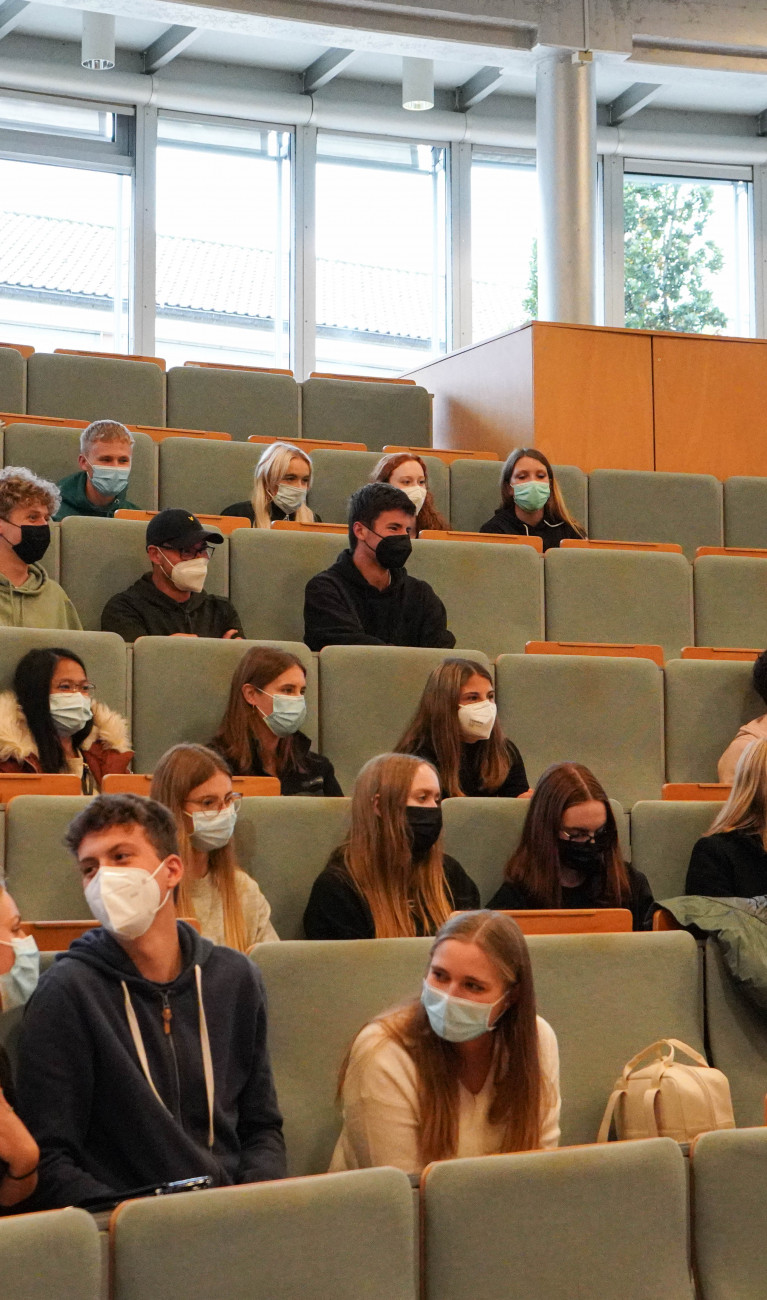 Studierende in großem Hörsaal mit Masken