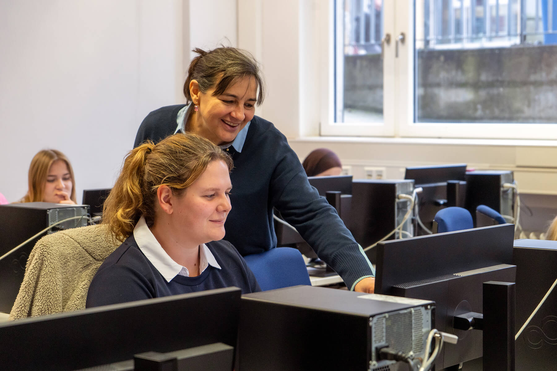 Dozentin Babett Reinhardt erläutert einer Studentin die Oberfläche von SAP am Computer