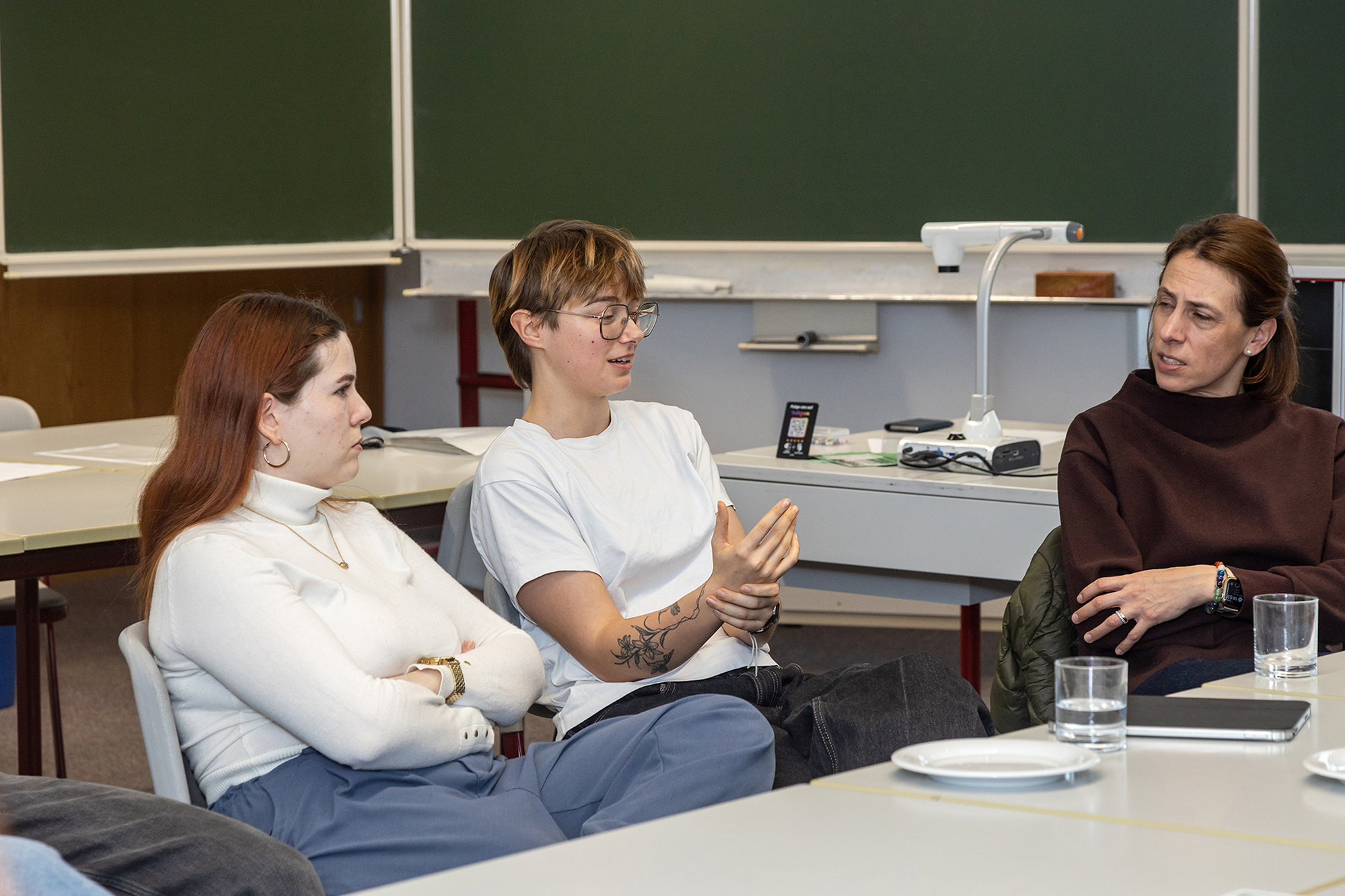 Zwei Schülerinnen diskutieren mit einer Lehrerin zum Thema Künstliche Intelligenz