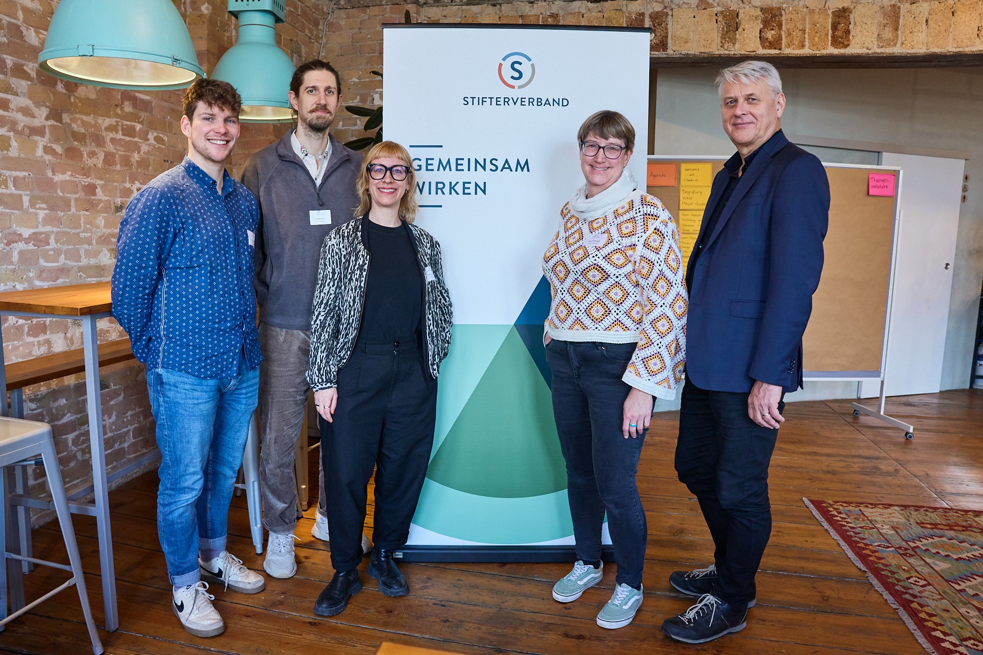 Fünf Personen stehen vor einem Banner