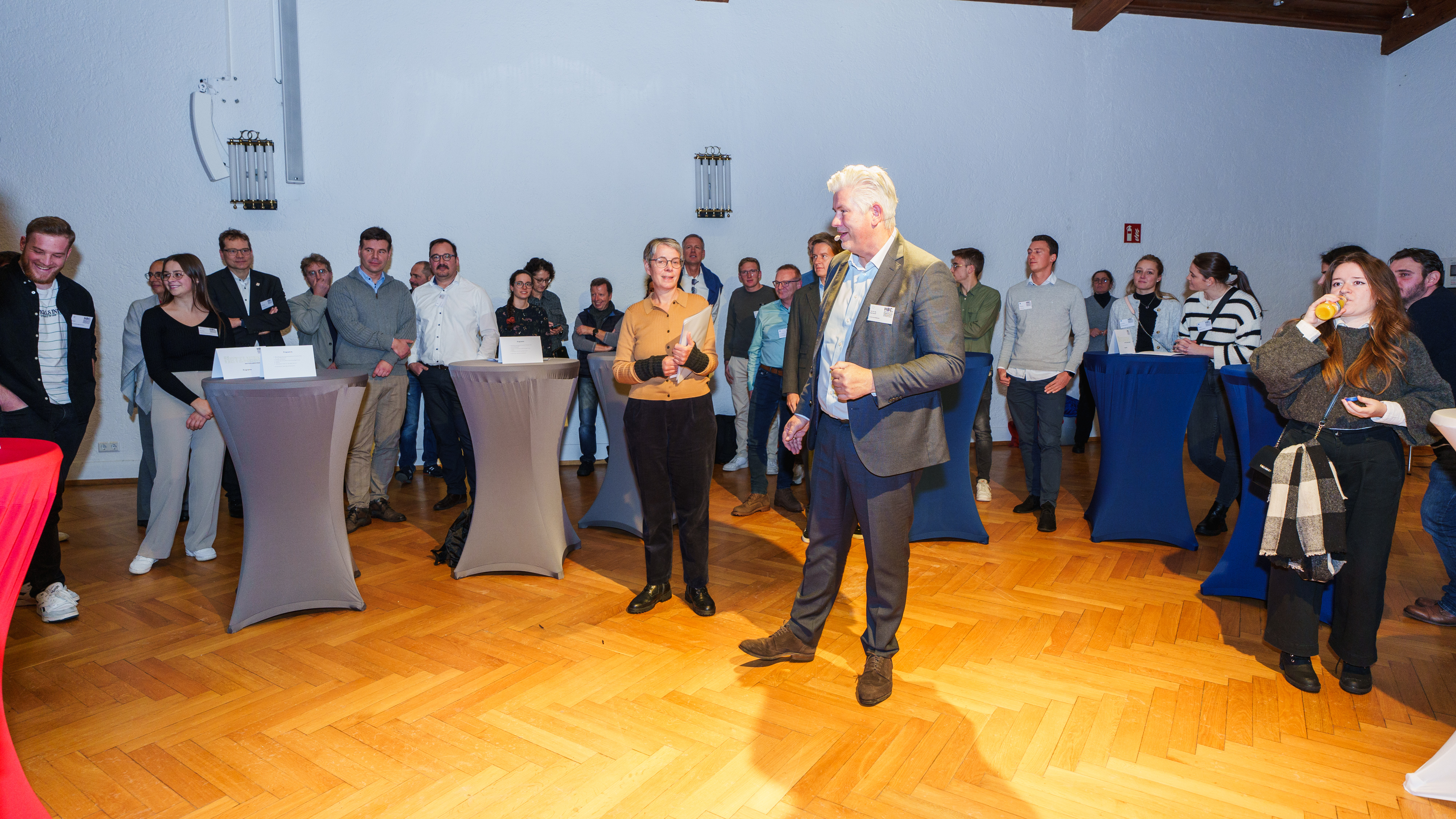 Mann steht in Mitte umgeben von Menschen und hält Ansprache