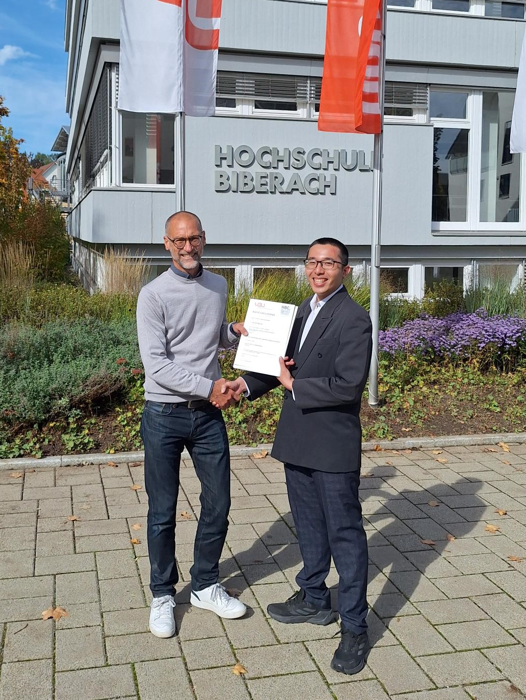 Zeugnisübergabe an einen Studenten