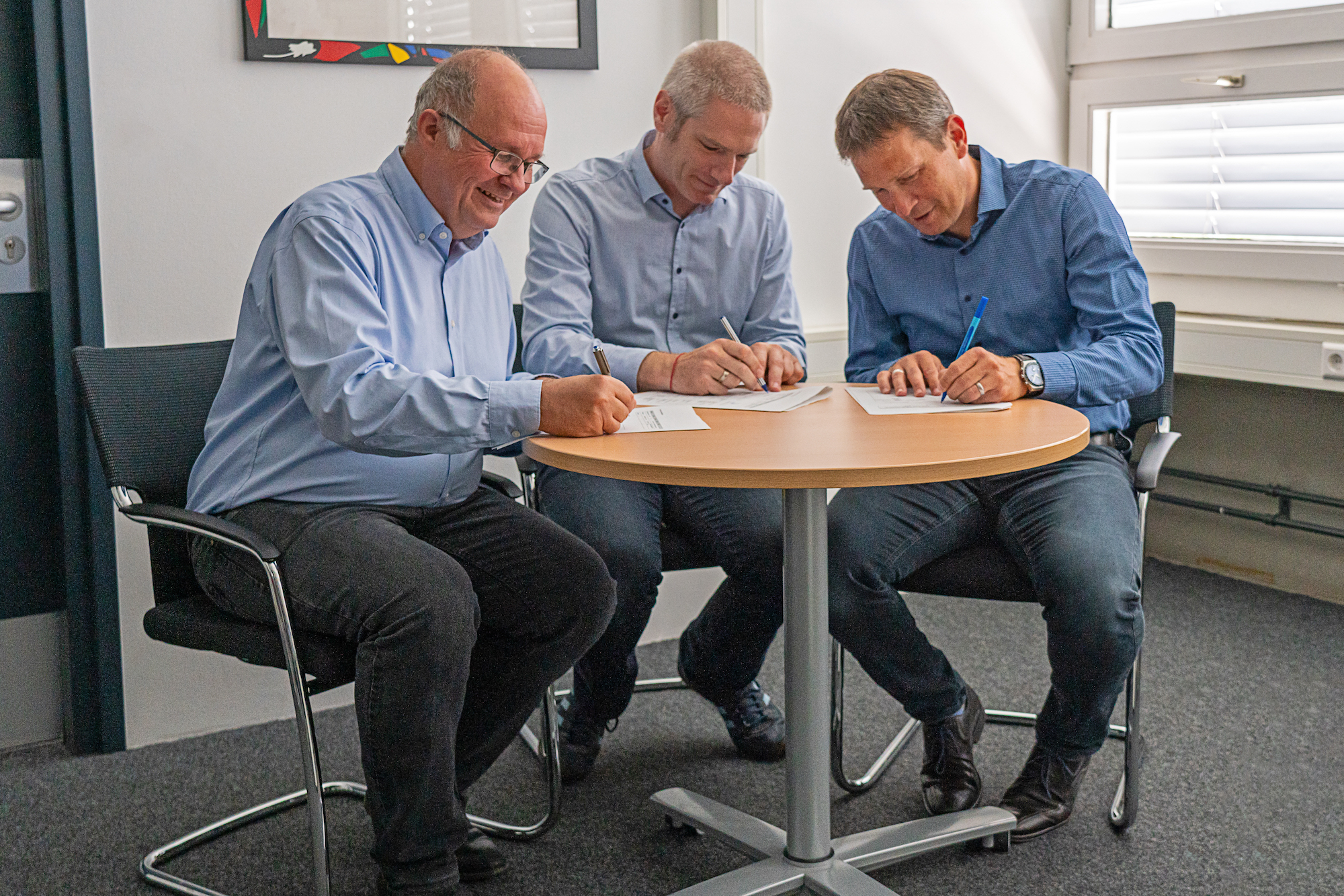 drei Männer unterzeichnen Vertrag an Tisch