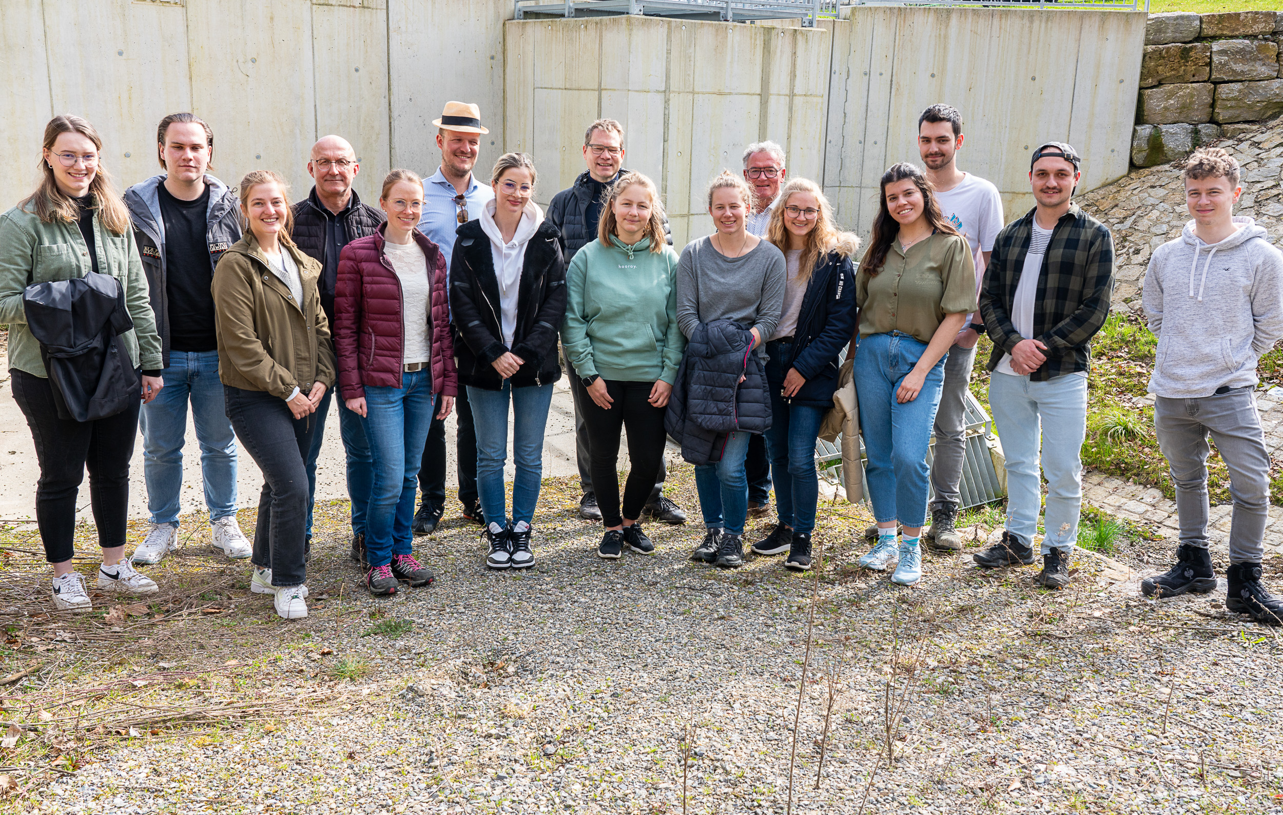 Eine große Gruppe steht draußen vor einem Staudamm