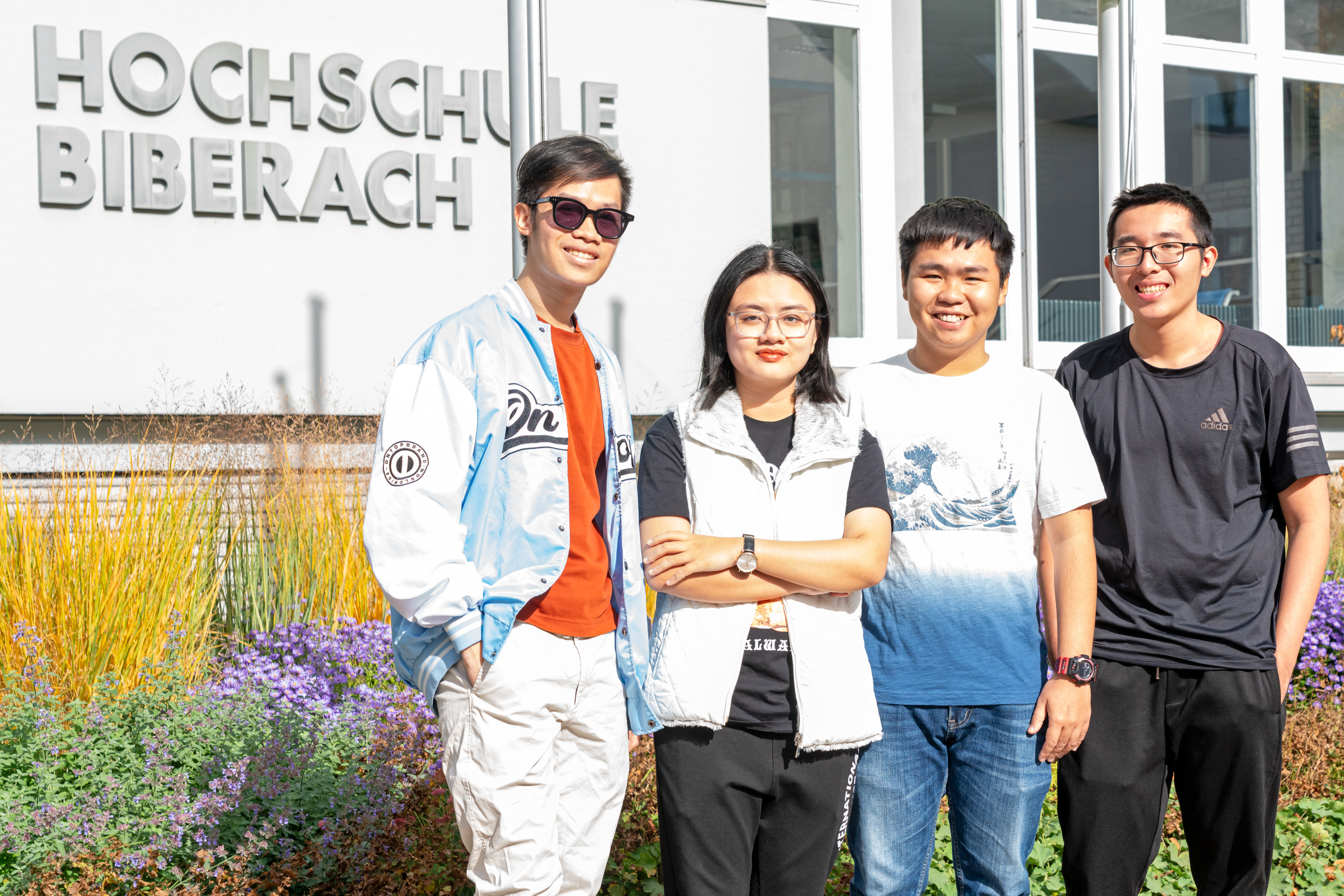 Studierende aus Vietnam stehend vor HBC-Schriftzug