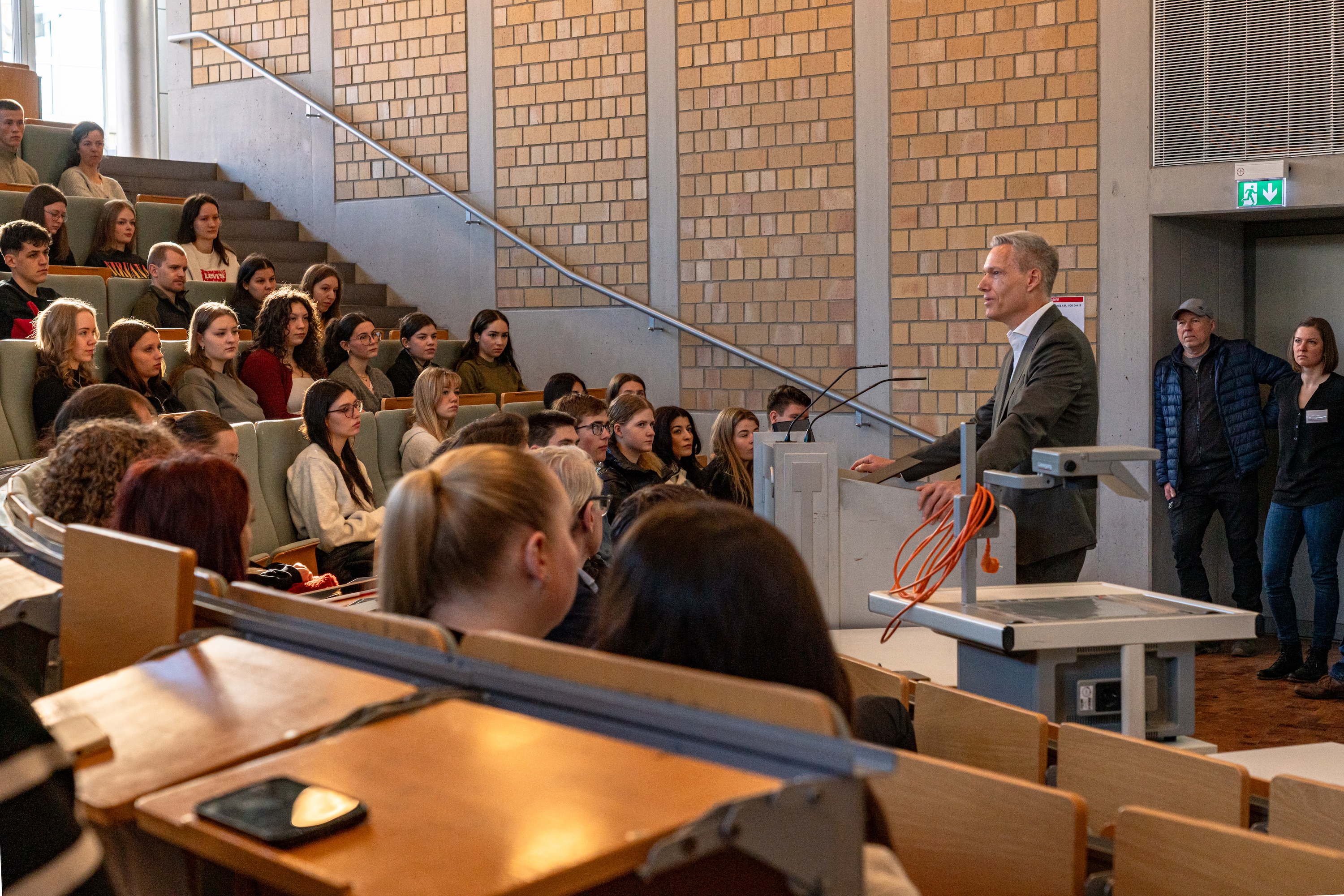 Studierende sitzen und stehen in einem Hörsaal