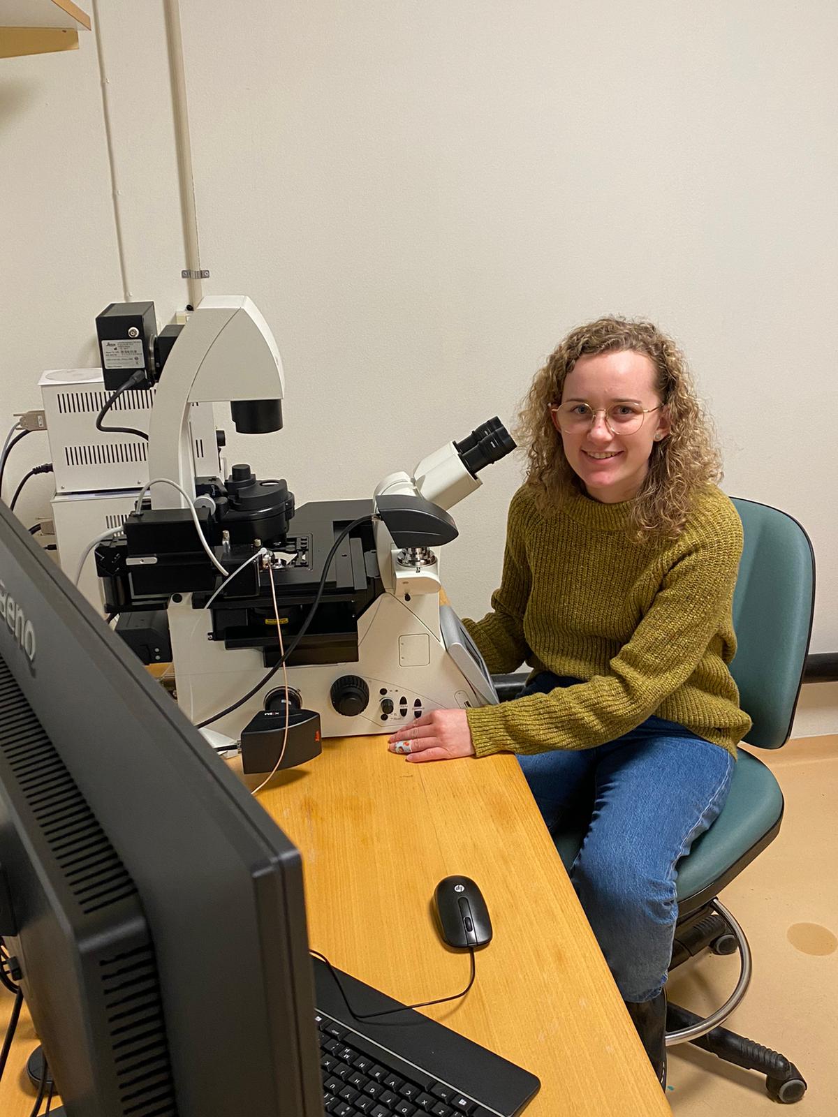 Studentin sitzt vor Mikroskop