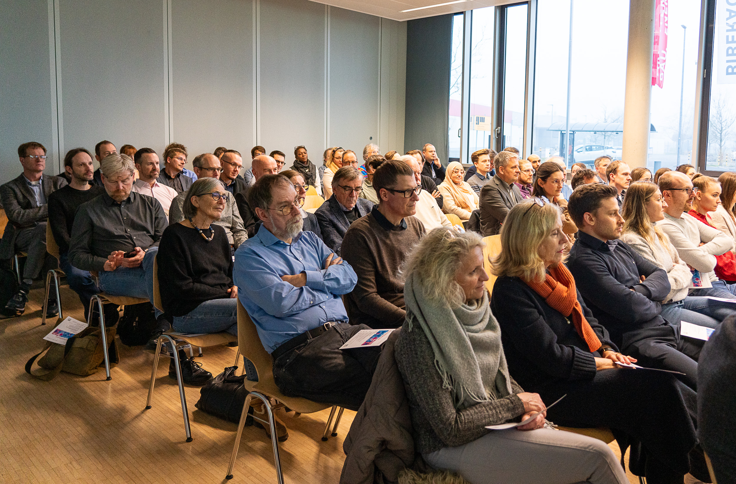 Personen sitzen bei einem Vortrag auf Stühlen