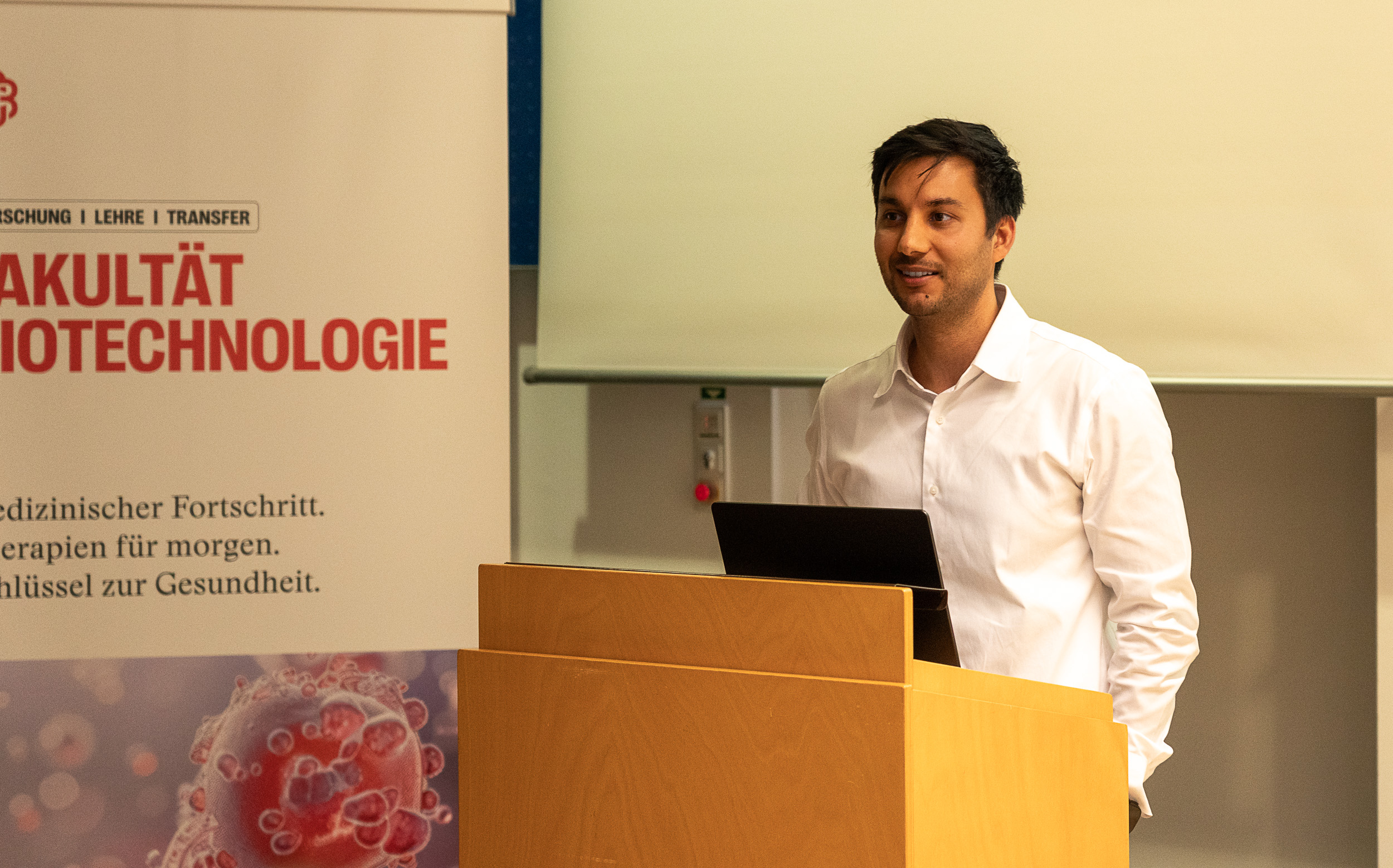 Ein Mann steht vor einem Pult und hält einen Vortrag