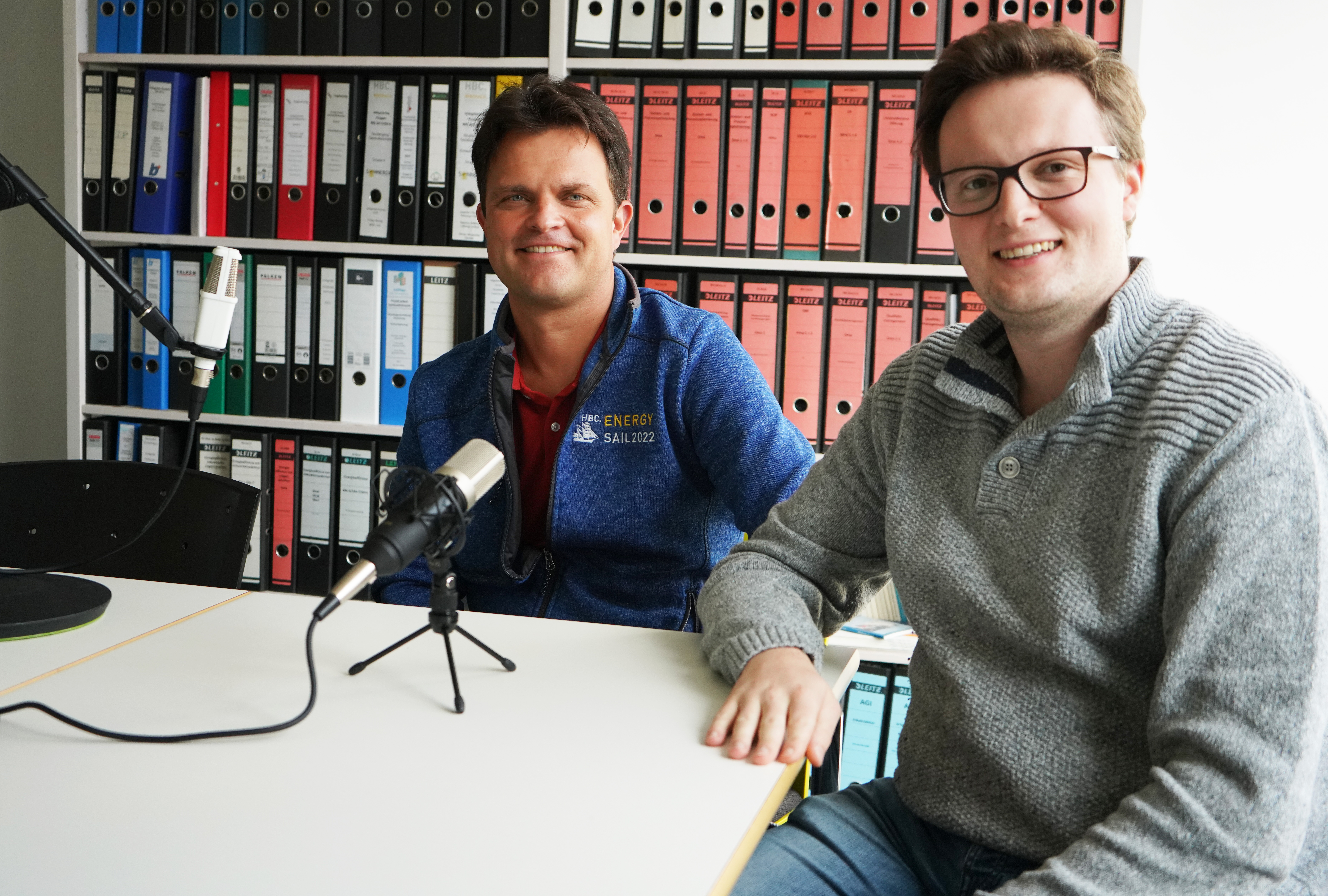 Zwei Männer an einem Tisch bei Podcast-Aufnahme