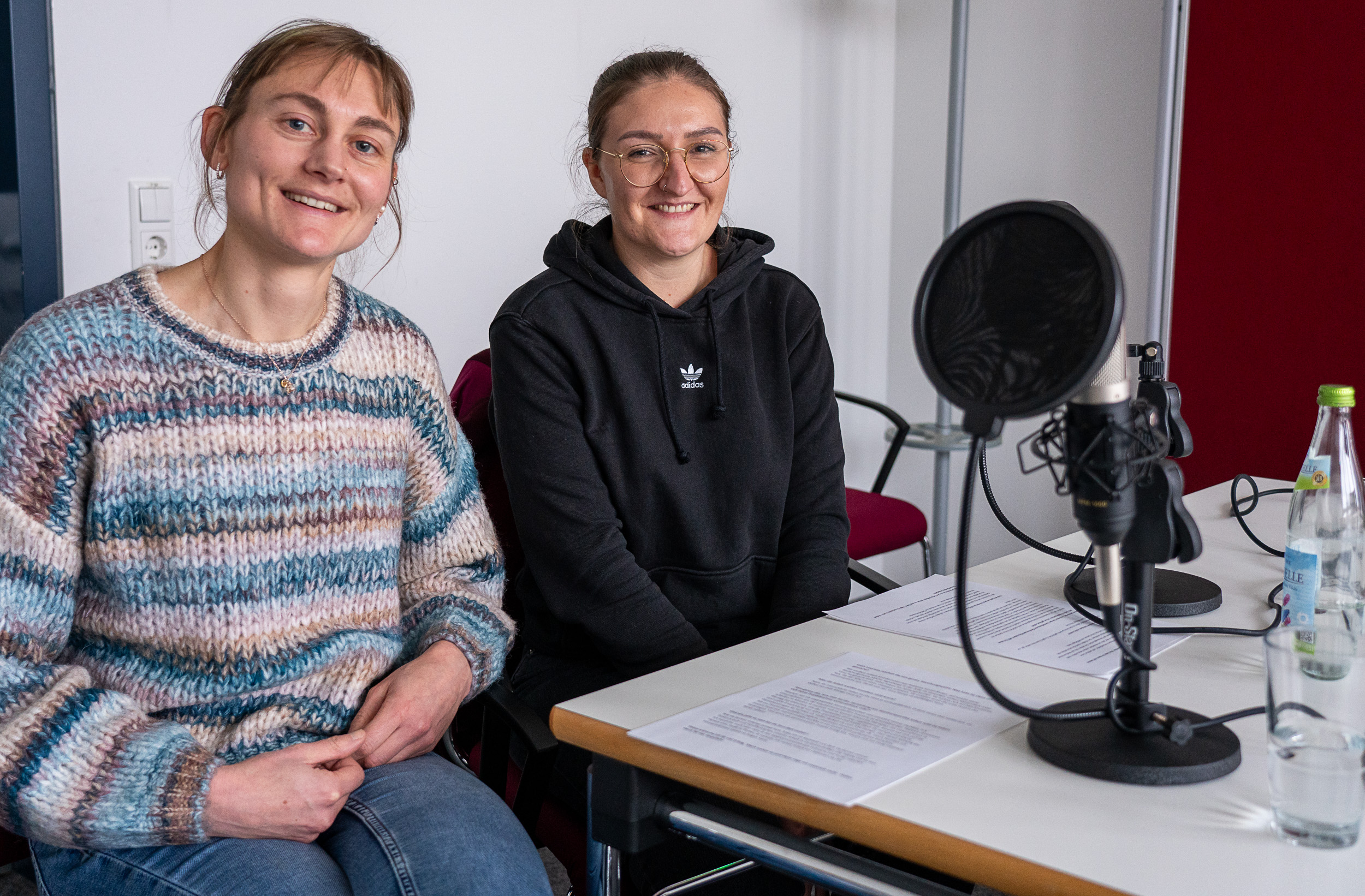 Zwei Frauen sitzen am Tisch bei einer Podcastaufnahme