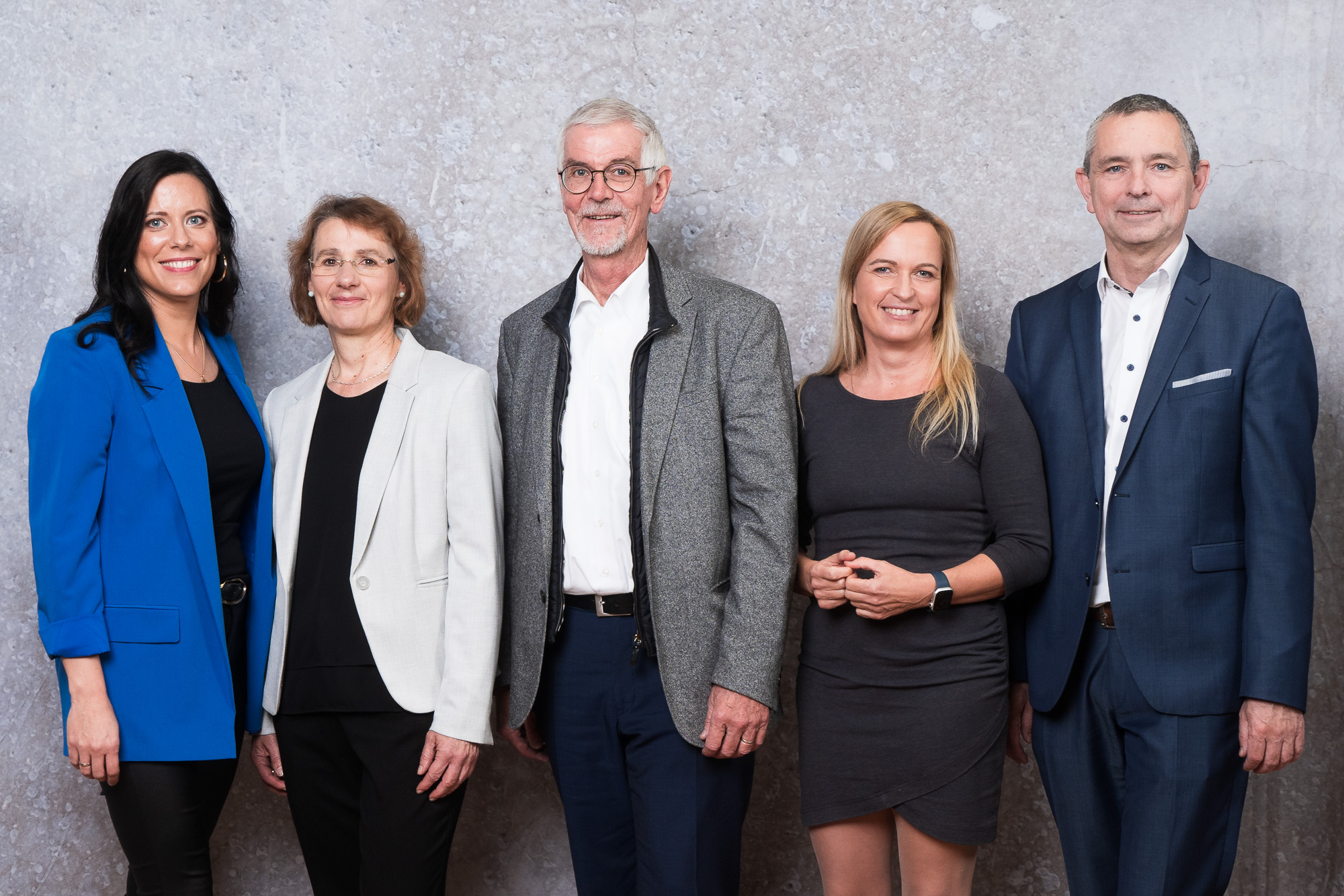 Drei Frauen und vier Männer stehen in einer Reihe, schick gekleidet