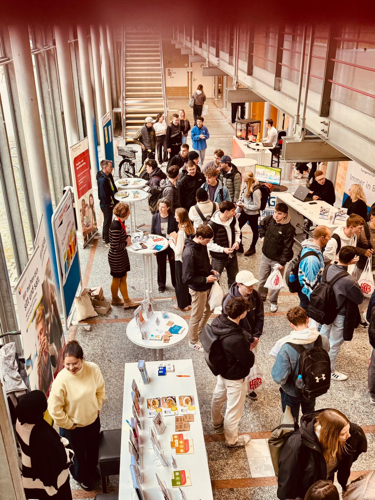 Viele Studierende stehen im Foyer und informieren sich an Ständen