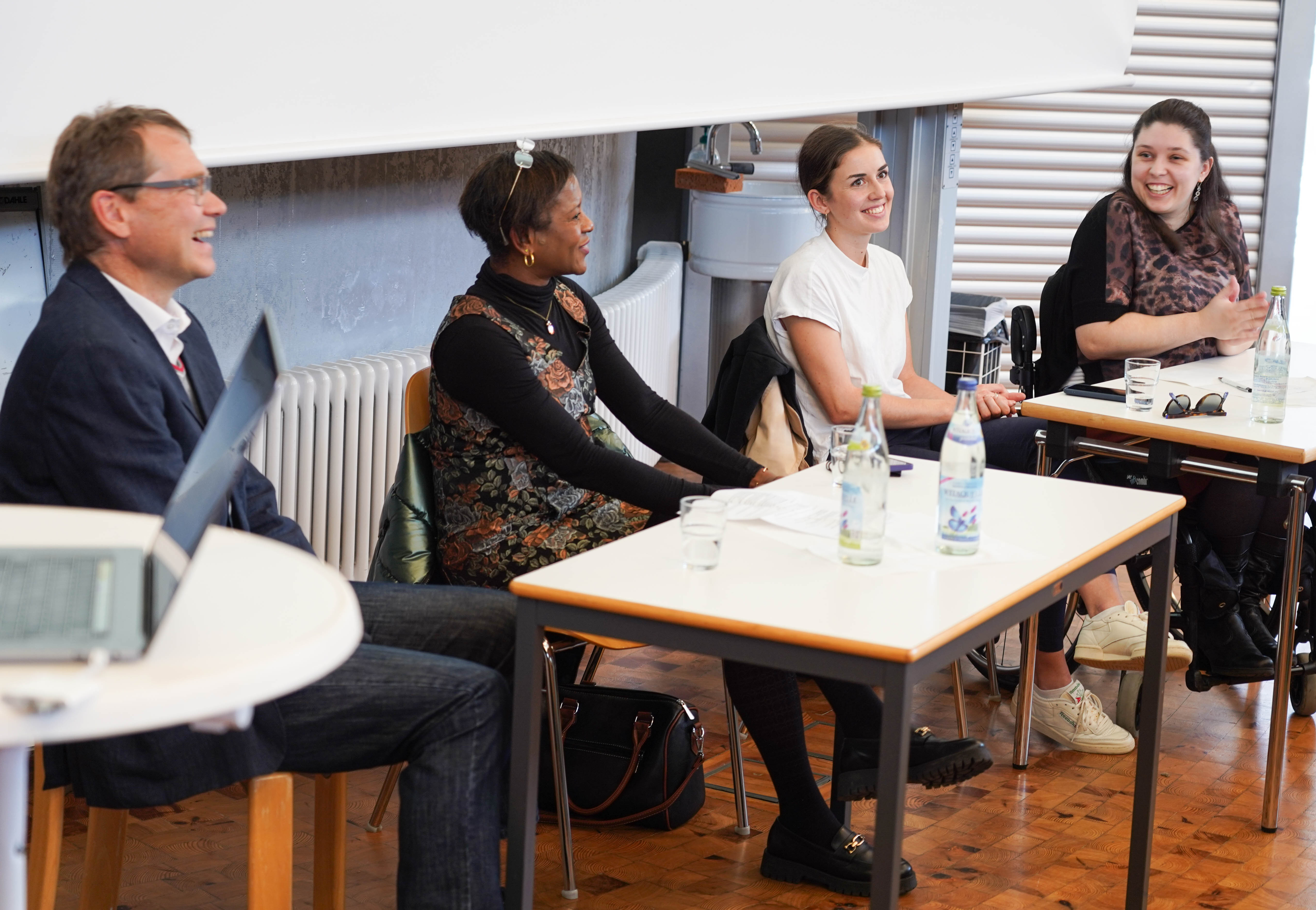 Vier Personen sitzend, lachend