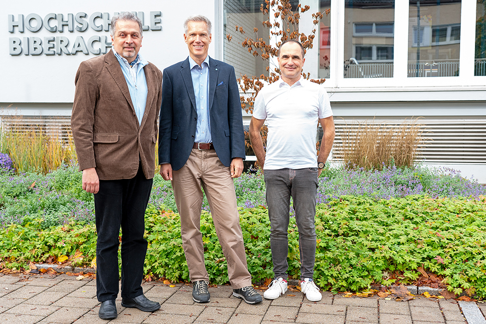 Drei Männer stehend draußen 