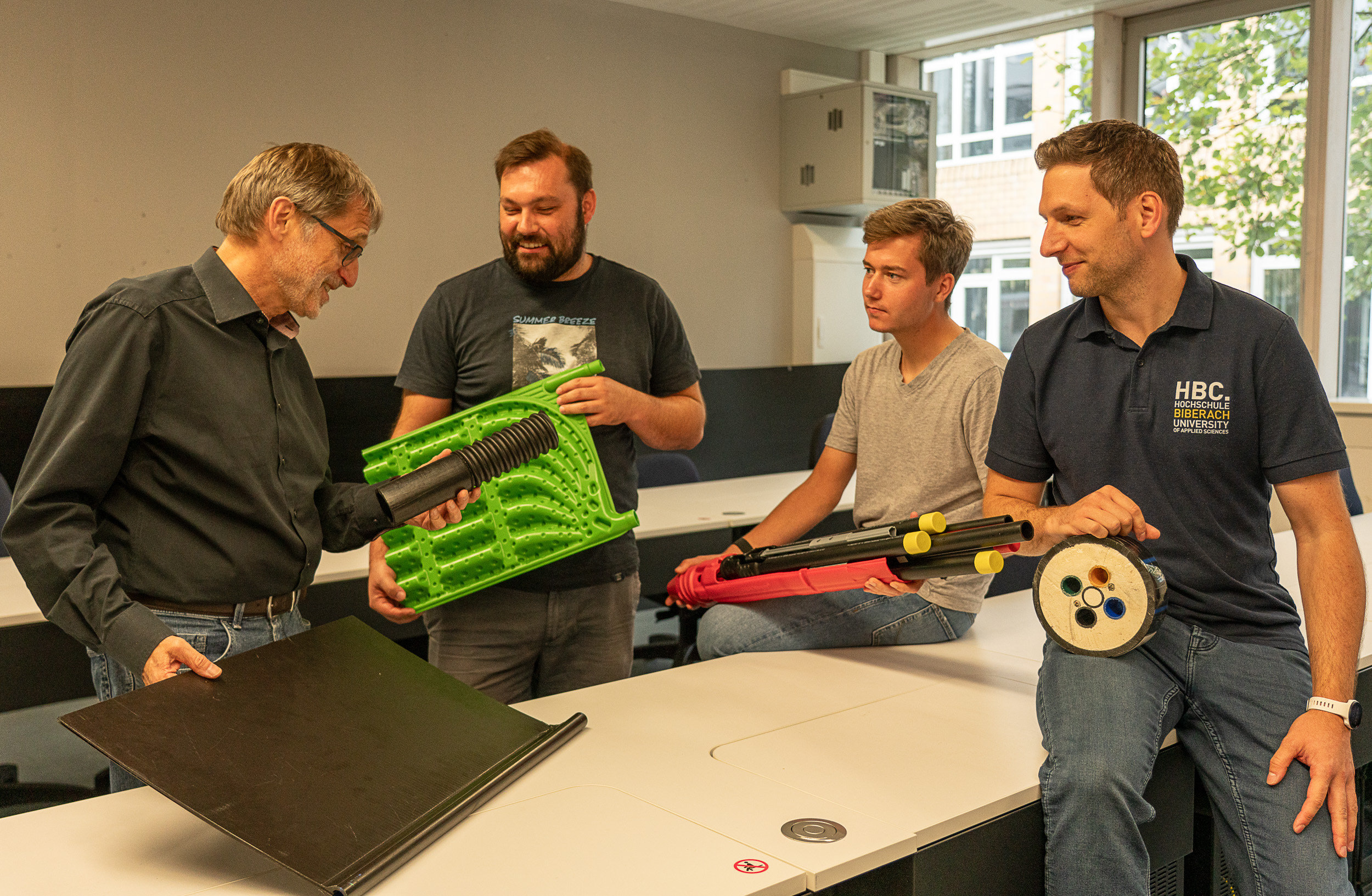 Vier Männer zeigen technisches Material 