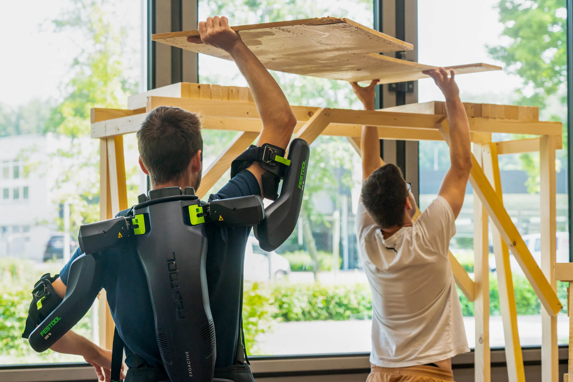 Zwei Studierende arbeiten Überkopf mit Exoskelett