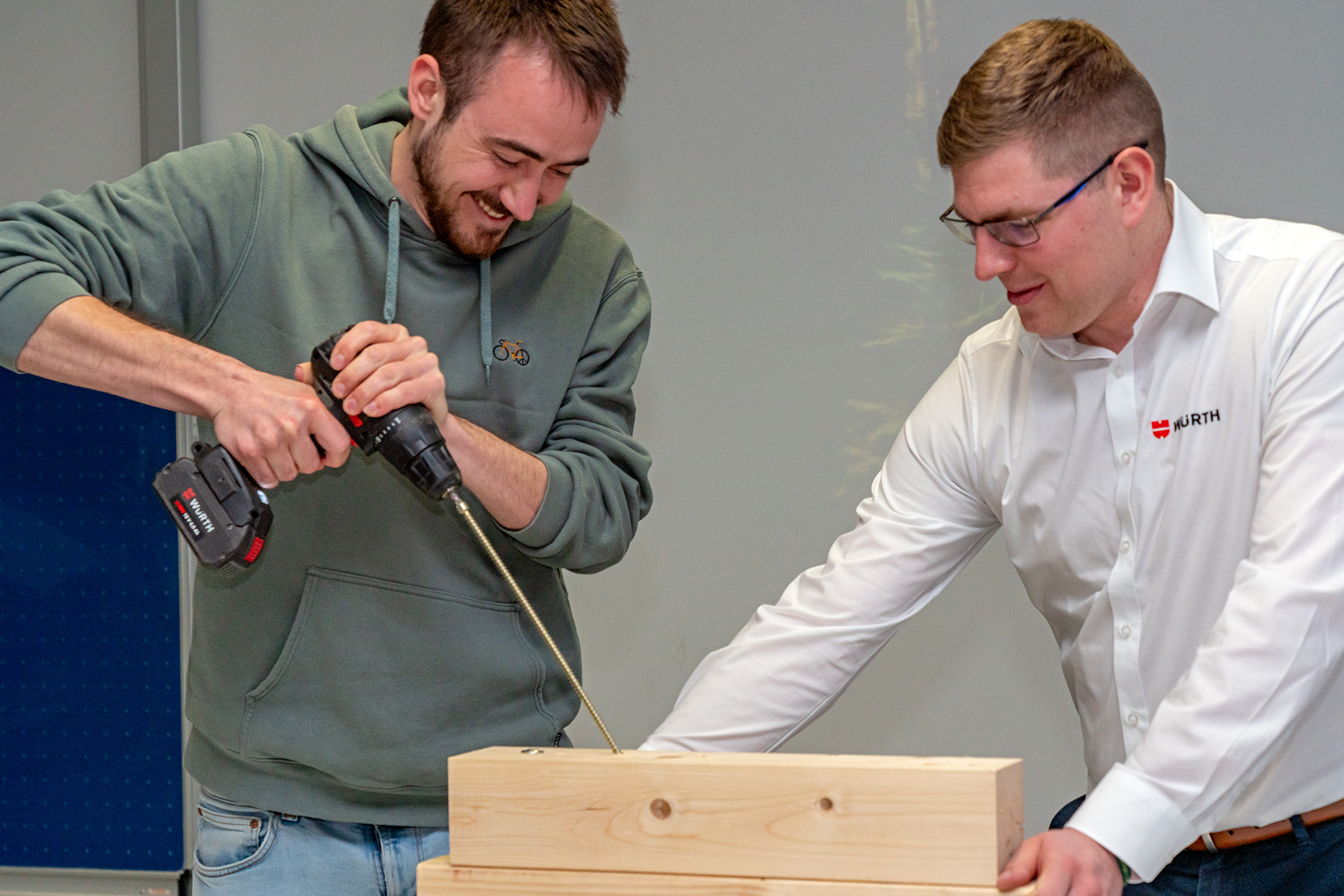 Studierender mit Würth-Vertreter schraubt lange Schraube in Holz