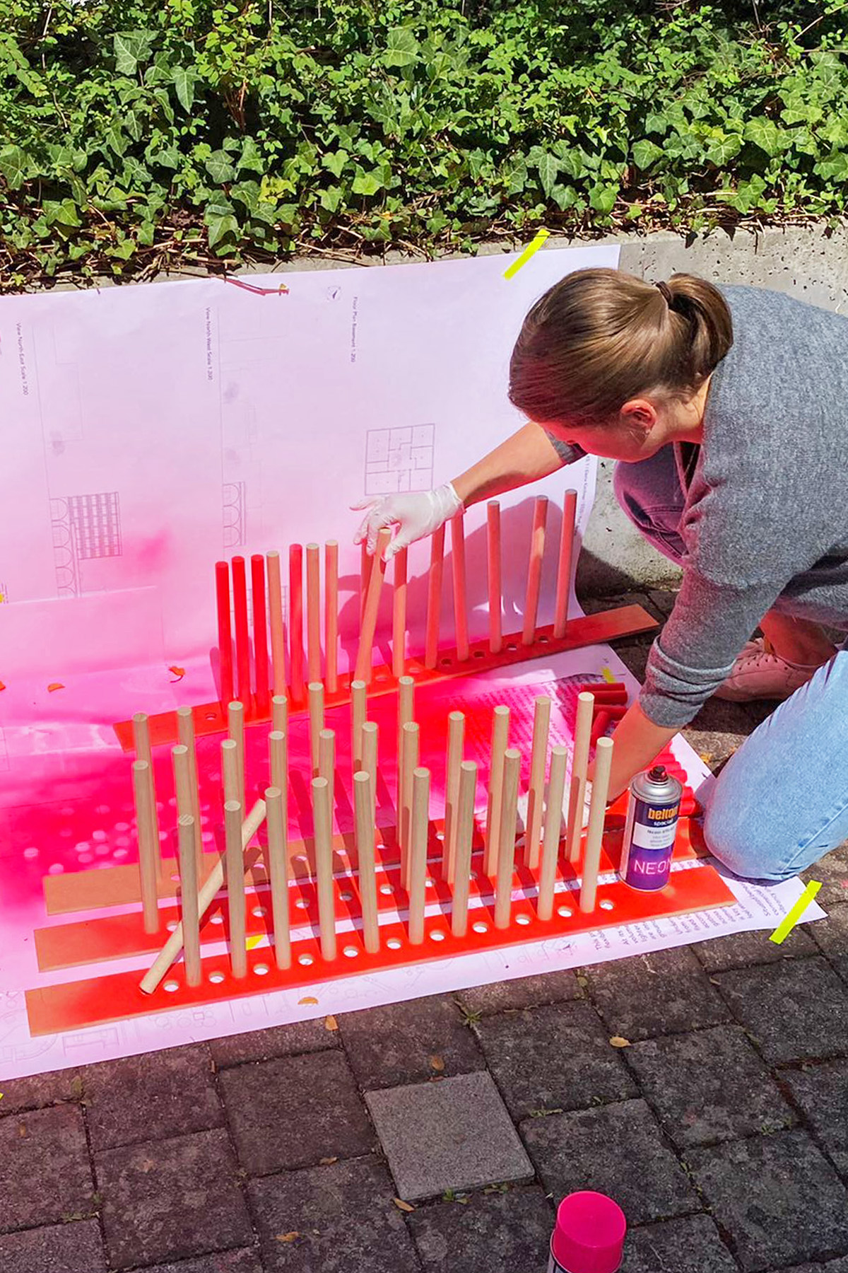 Eine Studierende bearbeitet Holzleisten mit pinker Sprayfarbe