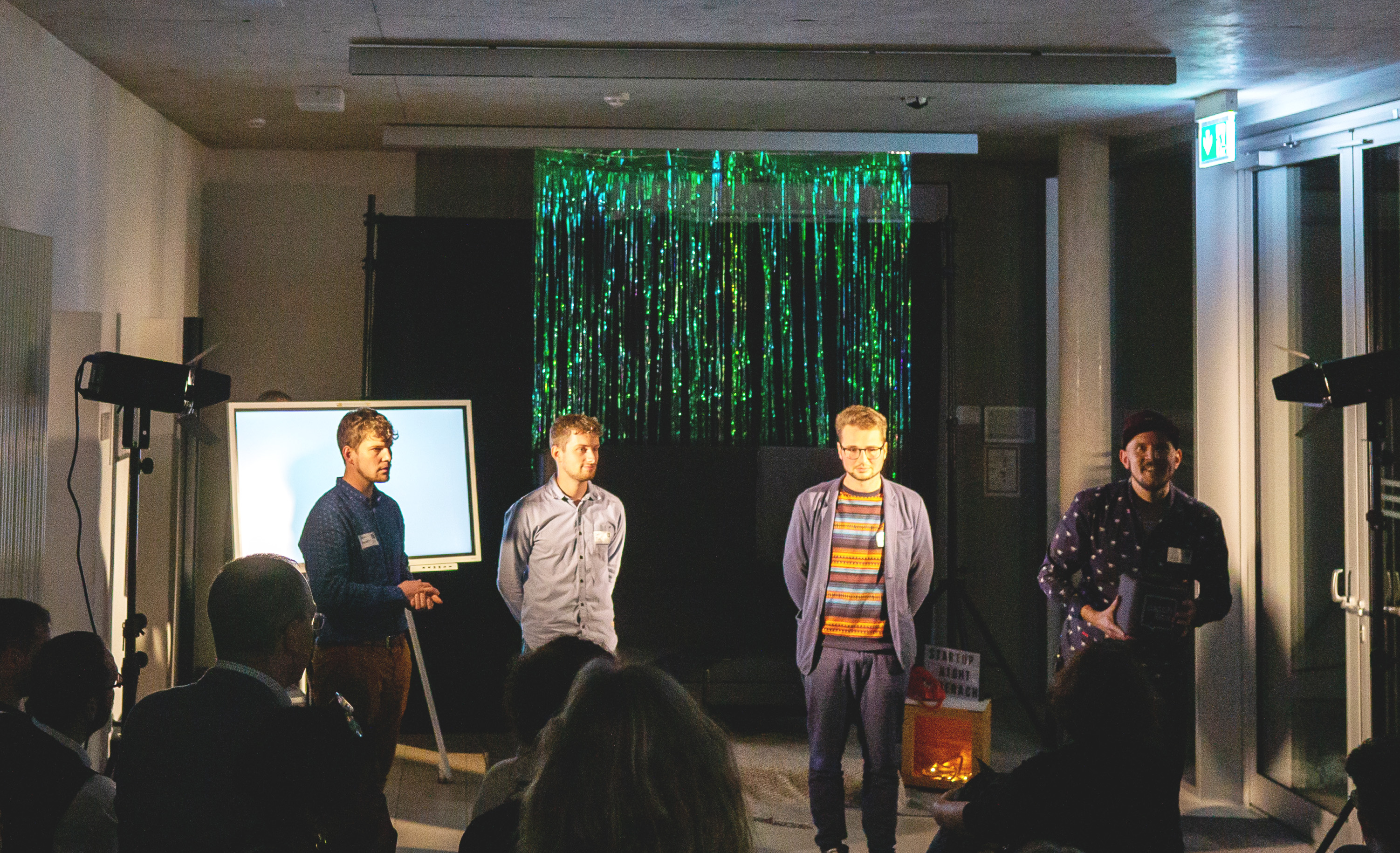 vier Männer auf beleuchteter Bühne