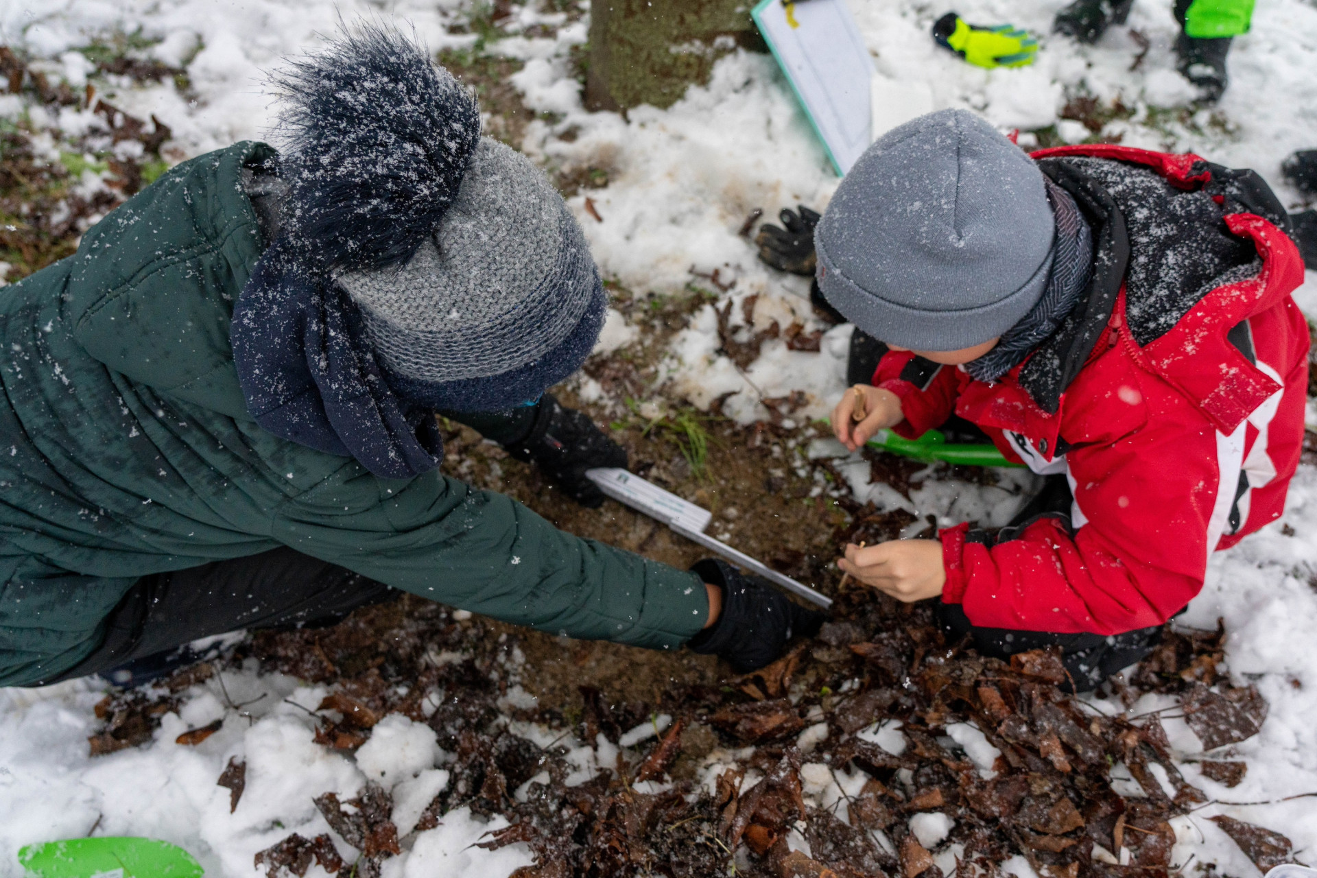 Zwei Jungen messen Loch in Erde aus