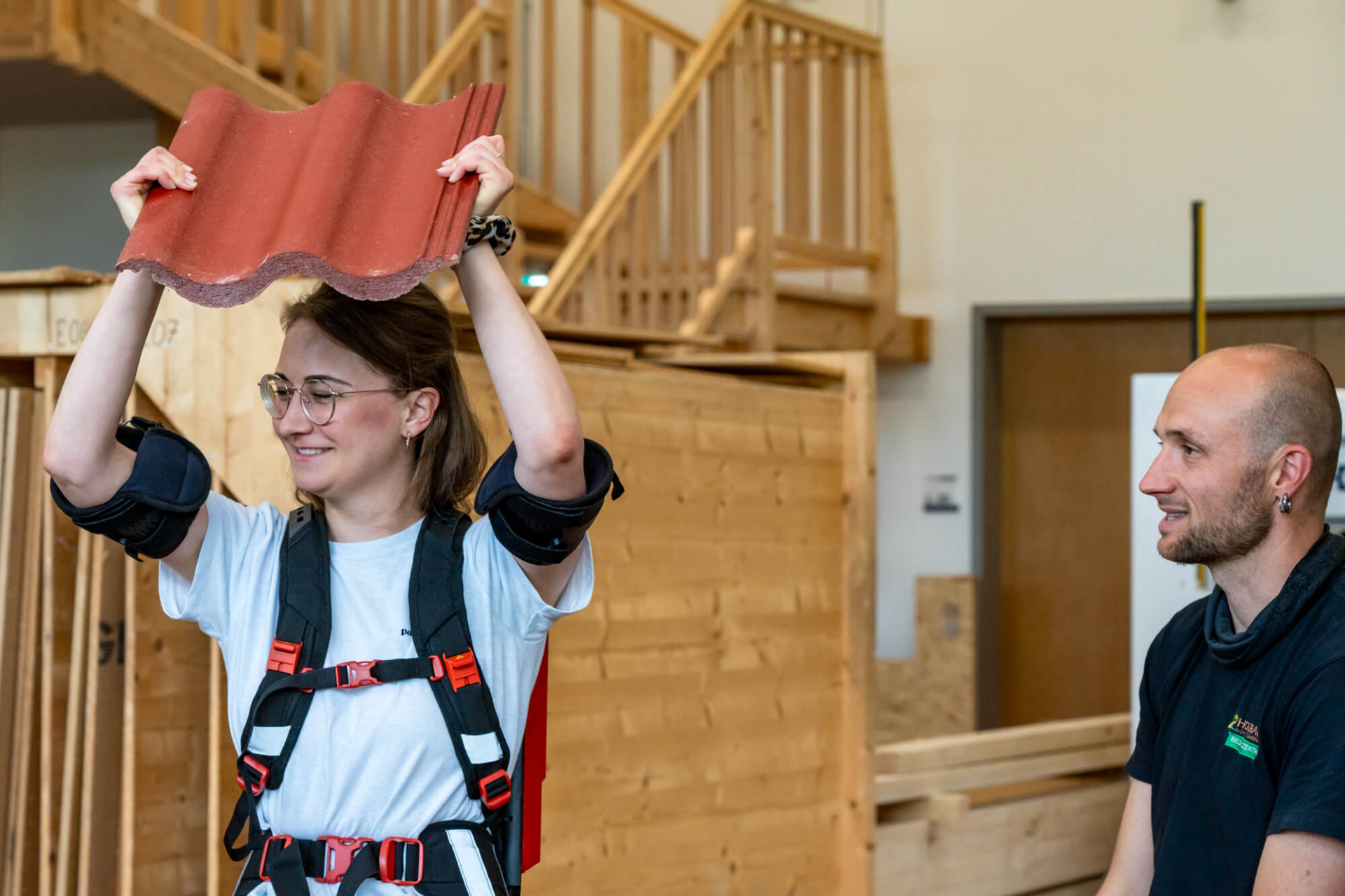 Ein Dachziegel wird von einer Studierenden mit Exosklett bequem in die Luft gehalten
