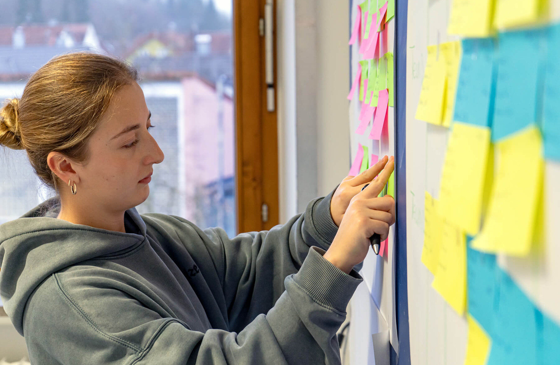 Eine Studierende sortiert Post-Its an der Wand um sich einen Überblick zum Thema SAP zu verschaffen