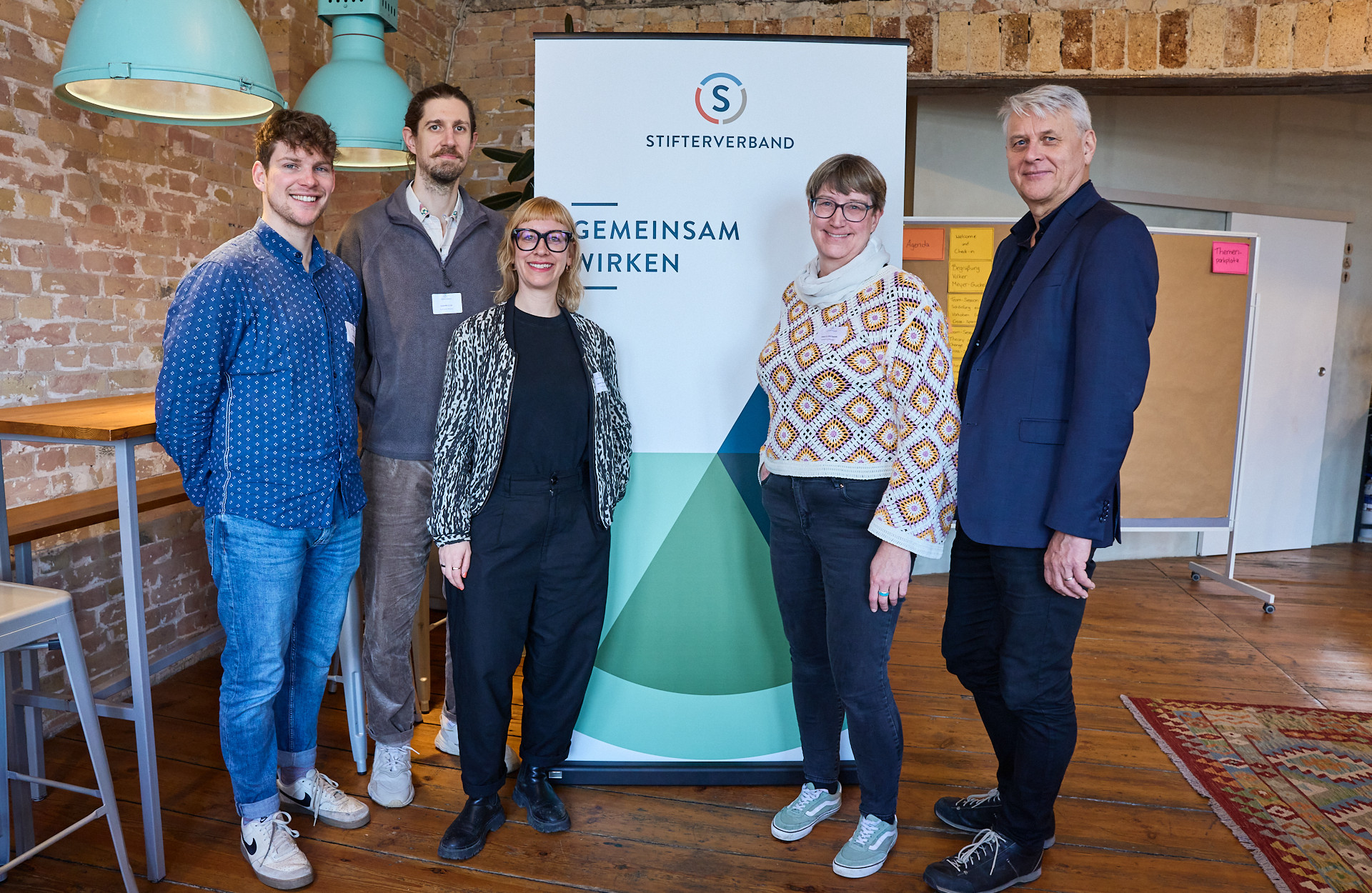 Fünf Personen stehen vor einem Banner