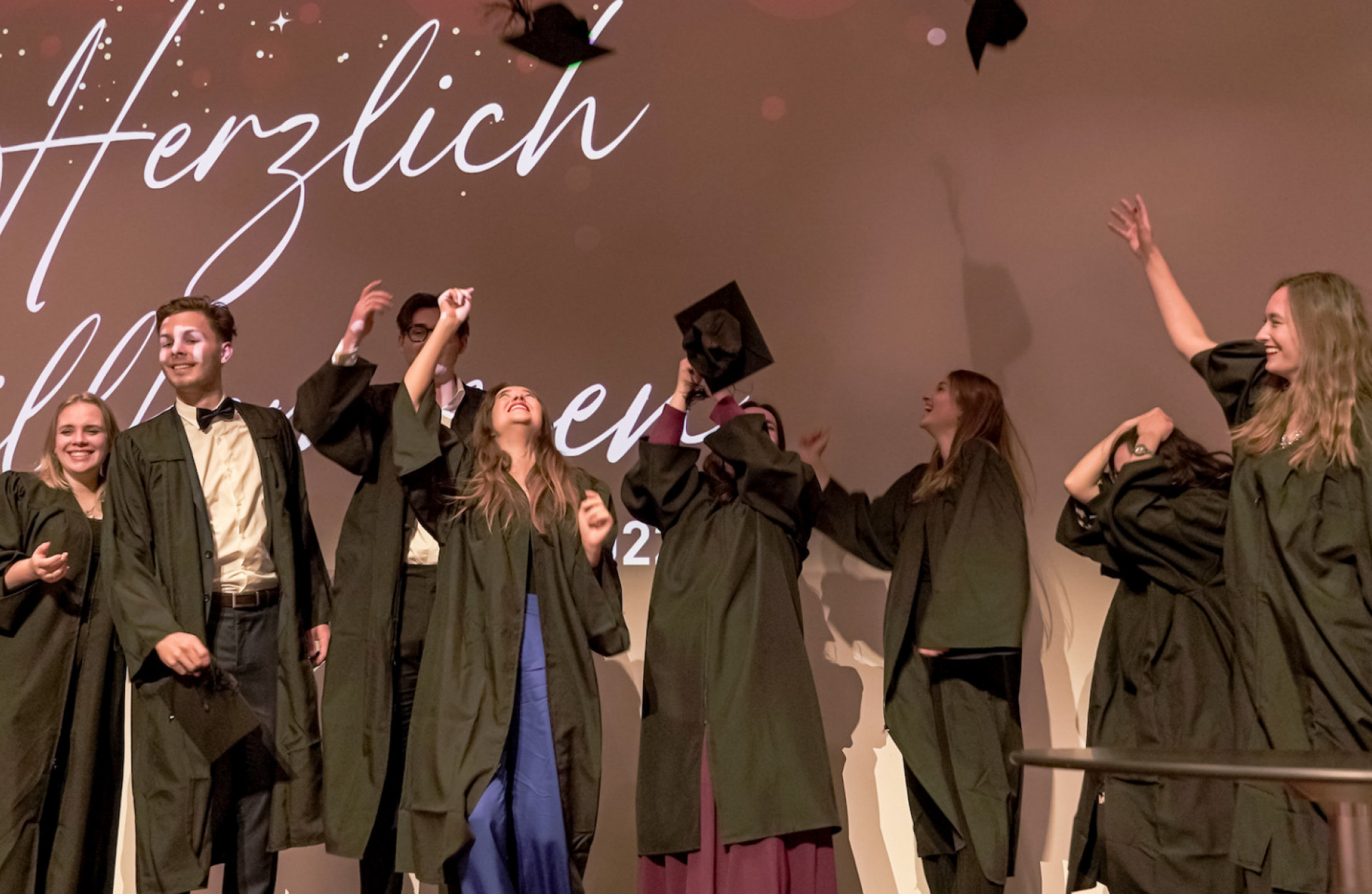 Absolvent*innen werfen Hüte in die Luft