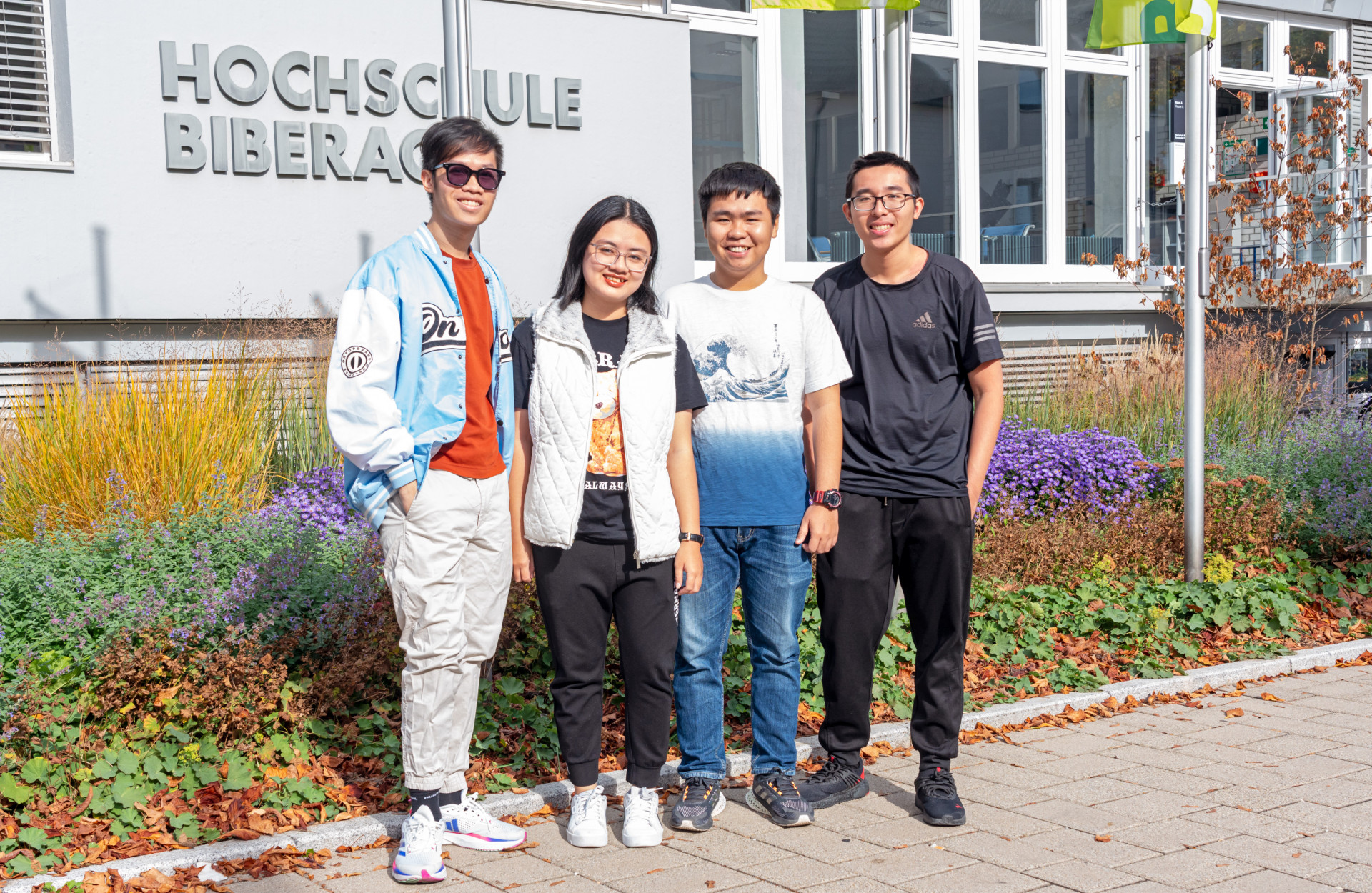 Studierende aus Vietnam stehend vor HBC-Schriftzug