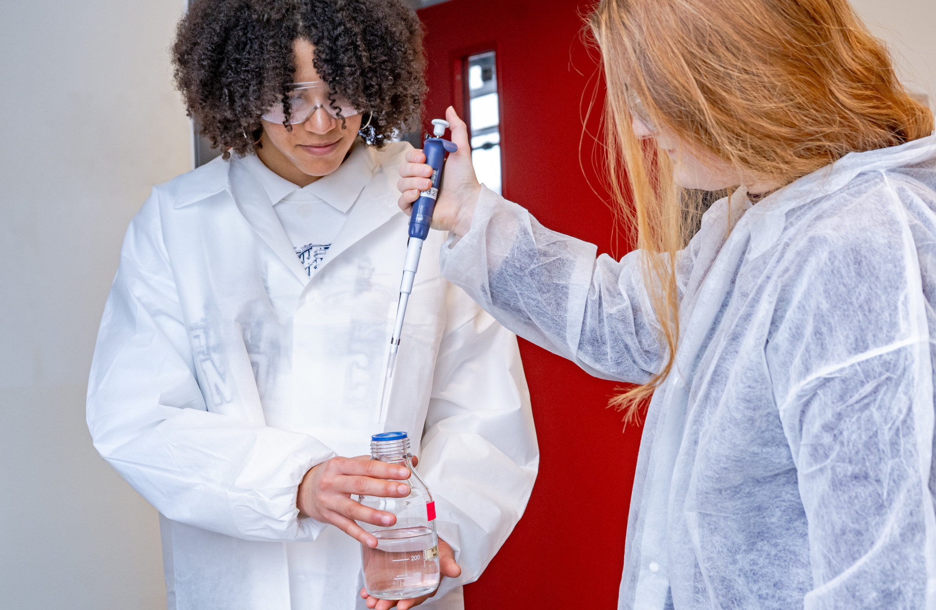 Zwei Schüler*innen führen einen Versuch durch im Labor