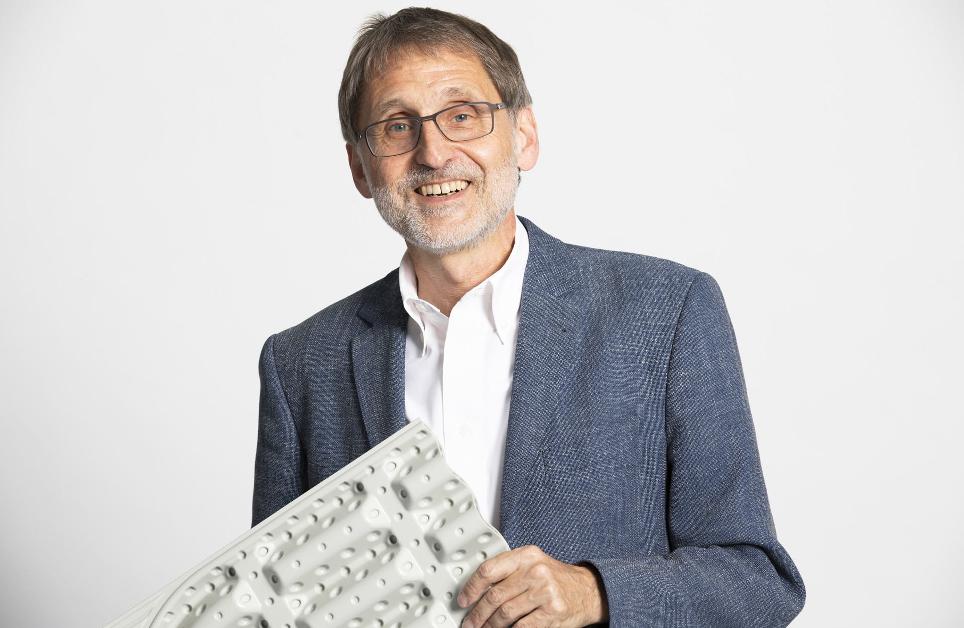 Ein Mann hält etwas in der Hand und lacht in die Kamera