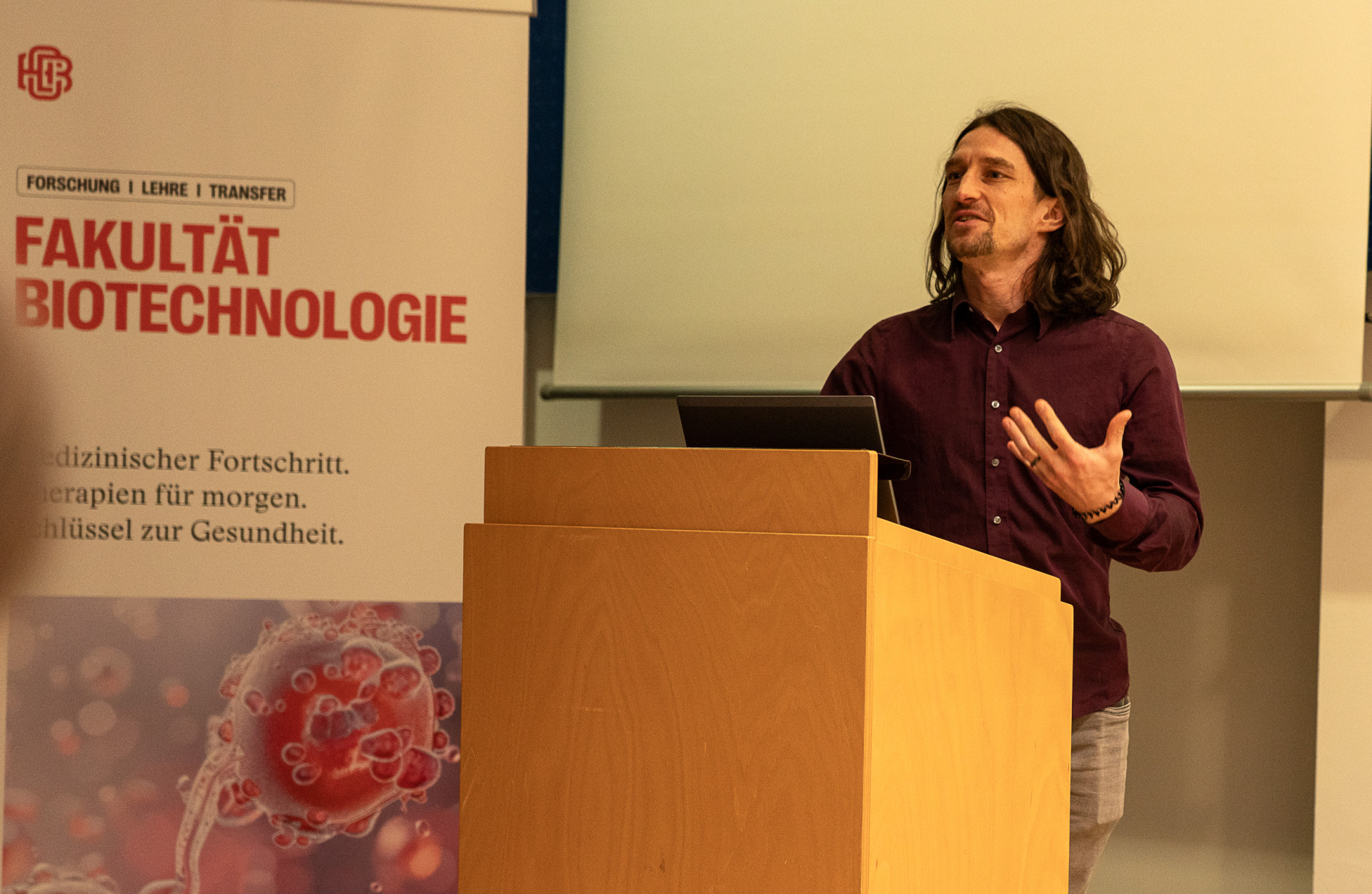 Ein Mann steht vor einem Pult und hält einen Vortrag