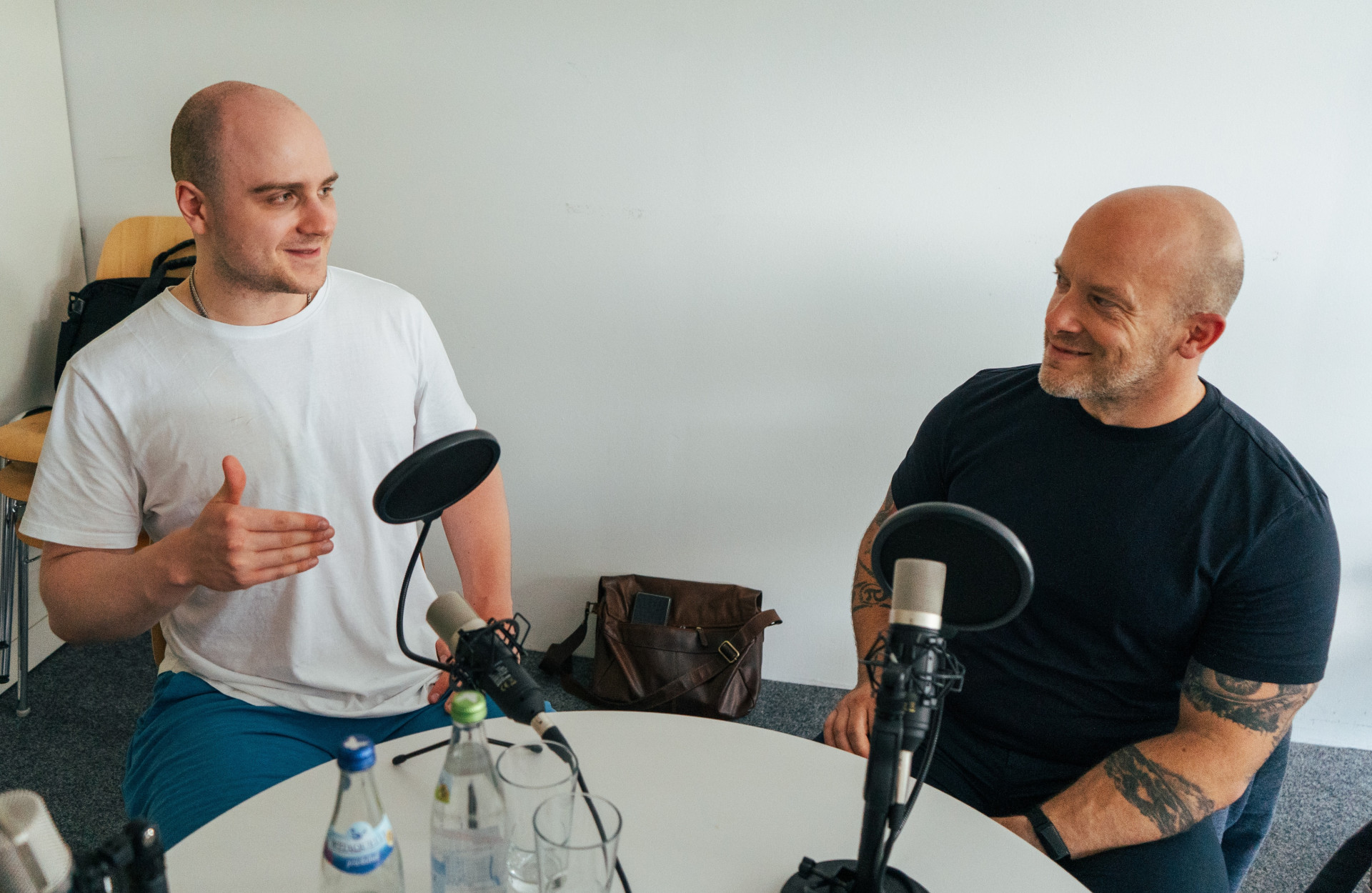 Zwei Männer sitzen an einem Tisch bei einer Podcastaufnahme