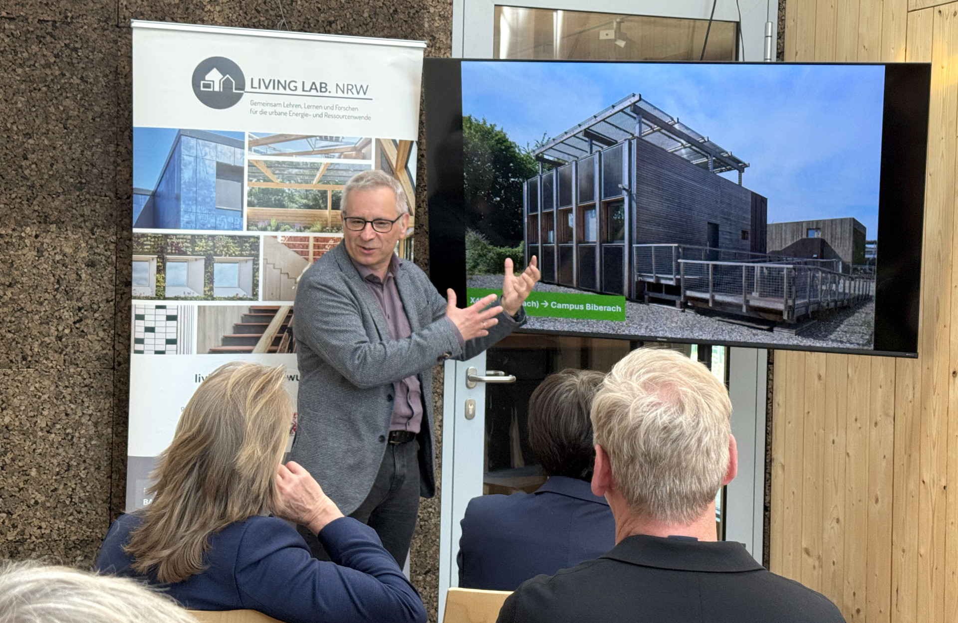 Ein Mann steht vor einem Bildschirm und erklärt etwas