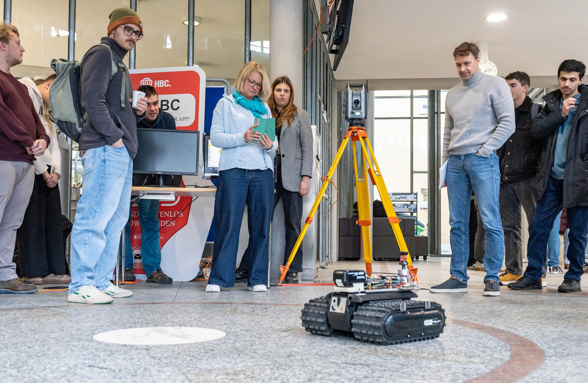 Eine Gruppe Studierender und Professor*innen steuert und filmt einen autonomen Roboter für die Baustelle