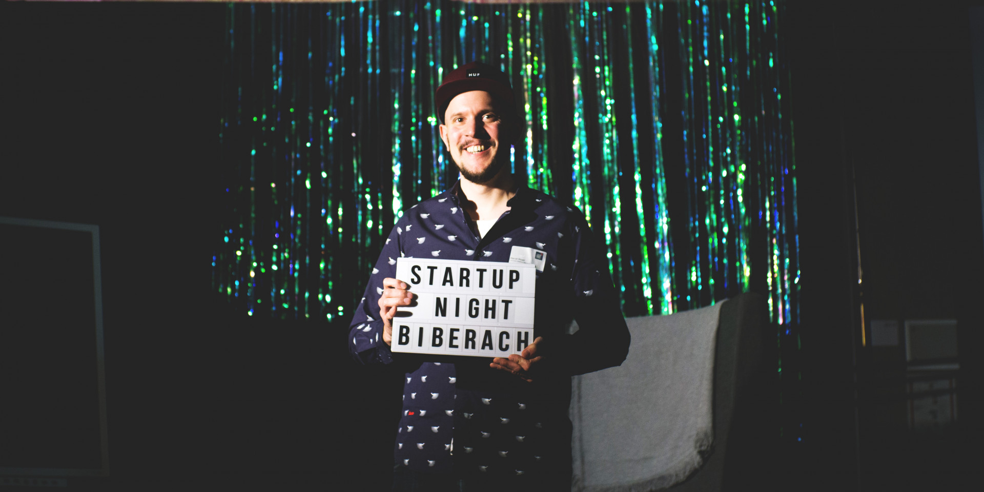 Mann vor glitzerndem Hintergrund mit Schild in der Hand