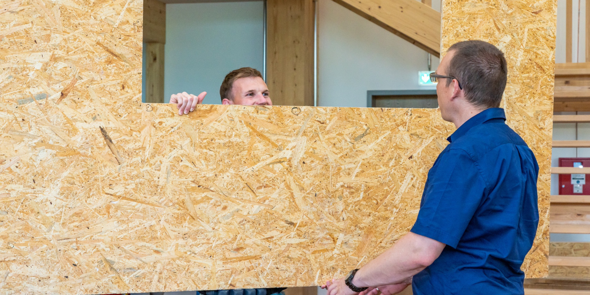 Zwei Männer tragen eine Holzwand
