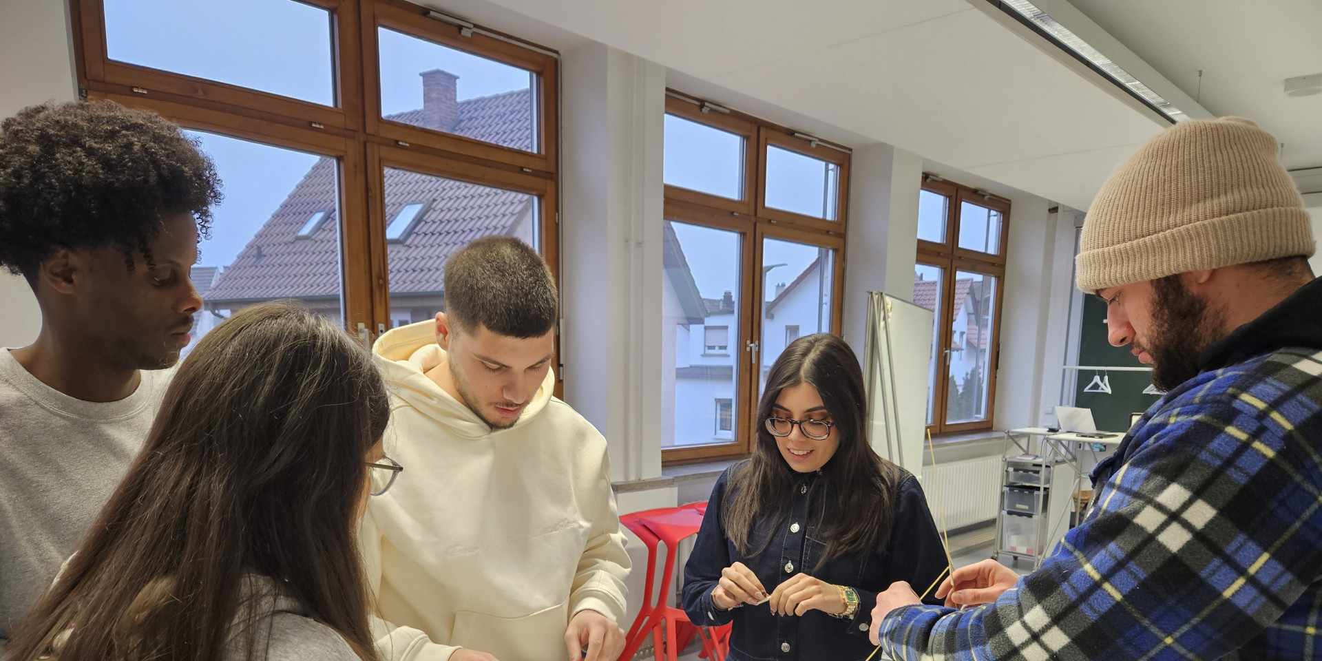 Studierende stehen an einem Tisch und basteln mit Marshmallows