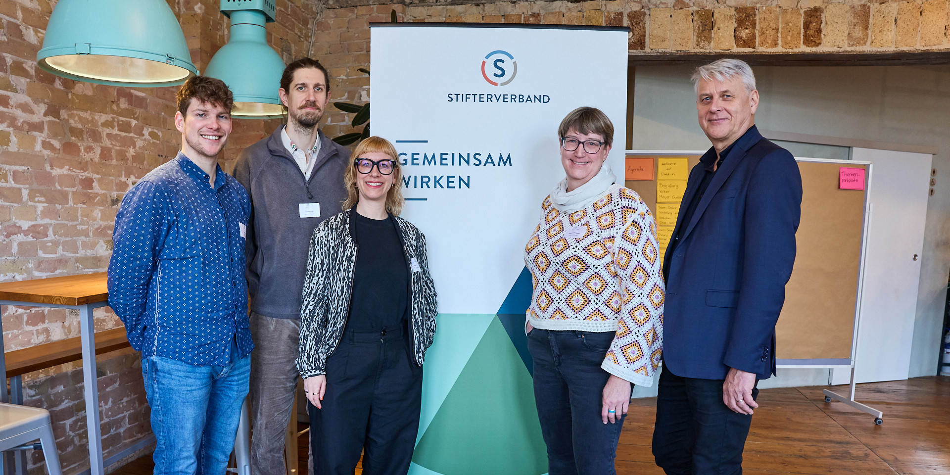 Fünf Personen stehen vor einem Banner