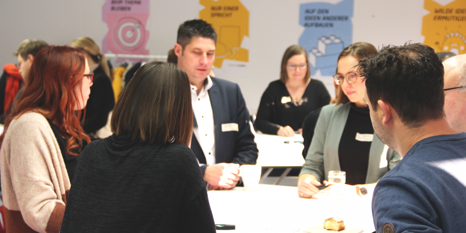 Erwachsene stehen um Tisch herum