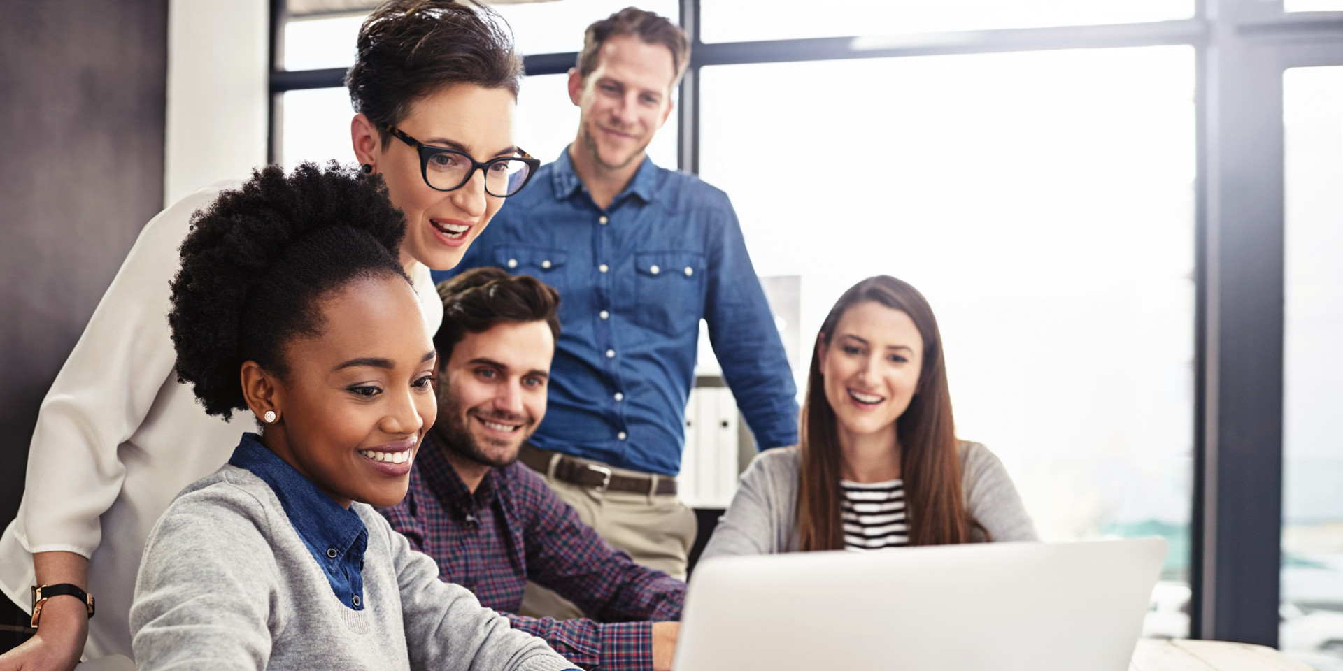 Fünf Personen verschiedener Nationalität sitzen vor einem Laptop