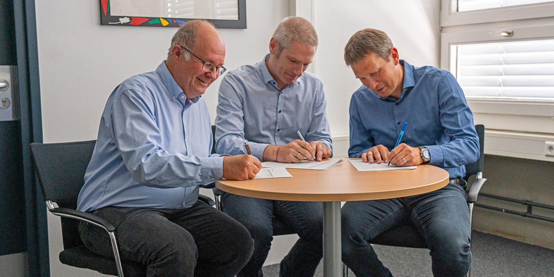drei Männer unterzeichnen Vertrag an Tisch