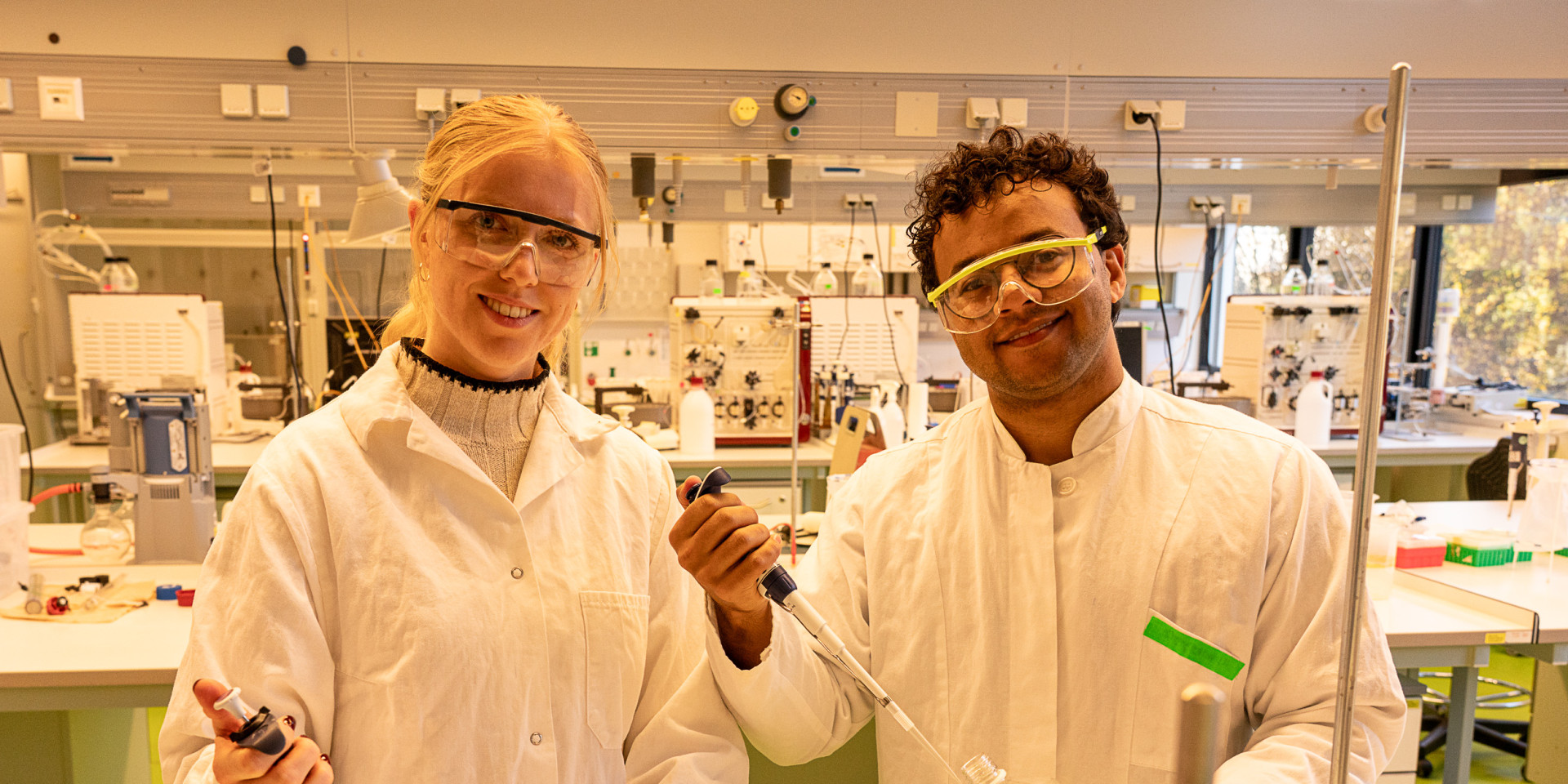 Eine junge Frau und ein junger Mann stehen im Labor und arbeiten