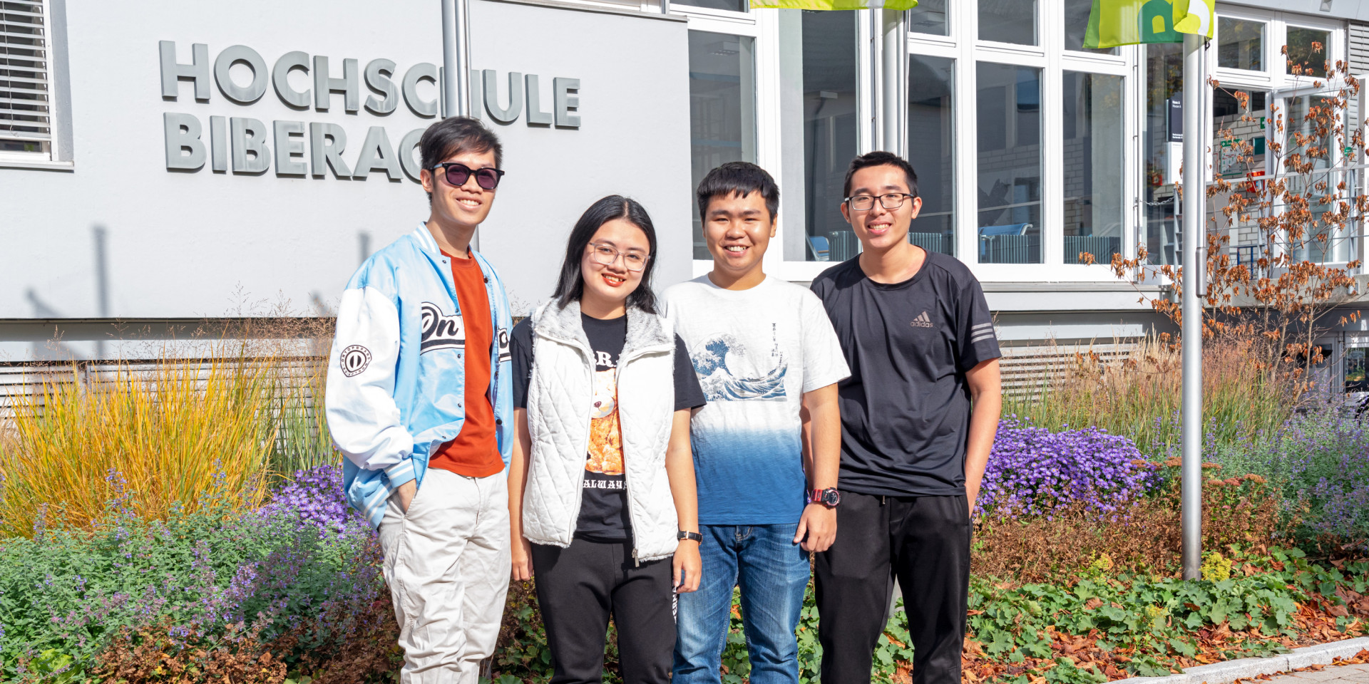 Studierende aus Vietnam stehend vor HBC-Schriftzug