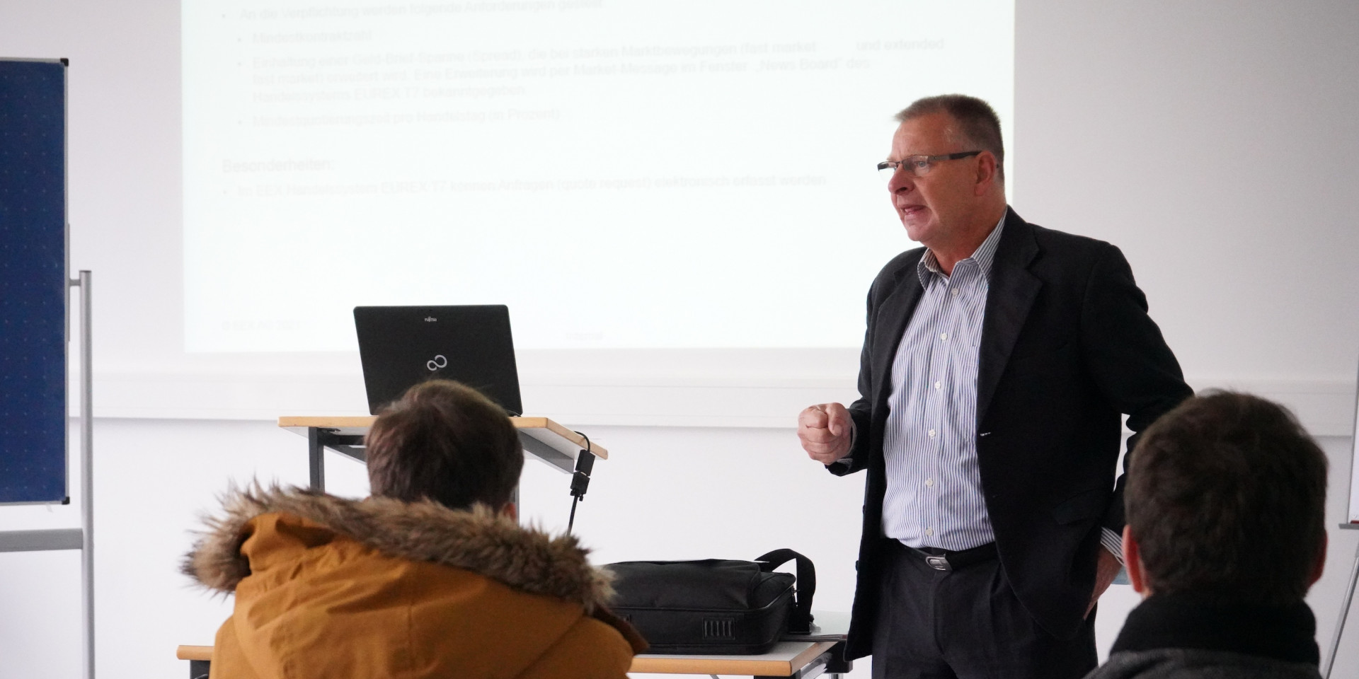 Mann steht vor Studierenden und hält Vortrag