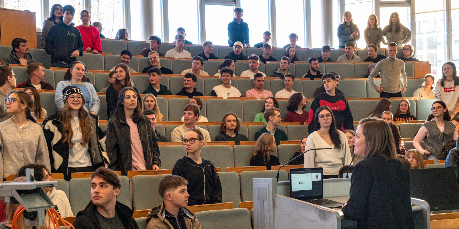 Studierende sitzen und stehen in einem Hörsaal