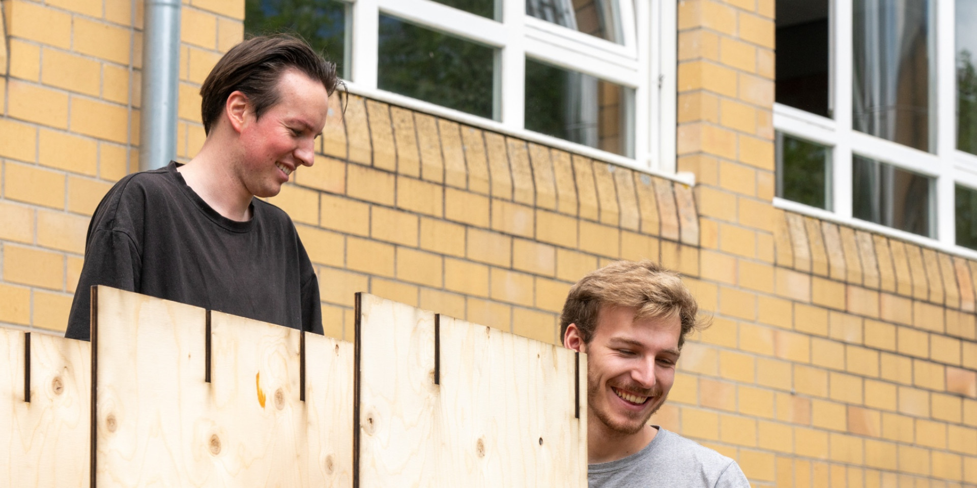 Zwei Studierende bauen ein Pavillon aus Holz auf 