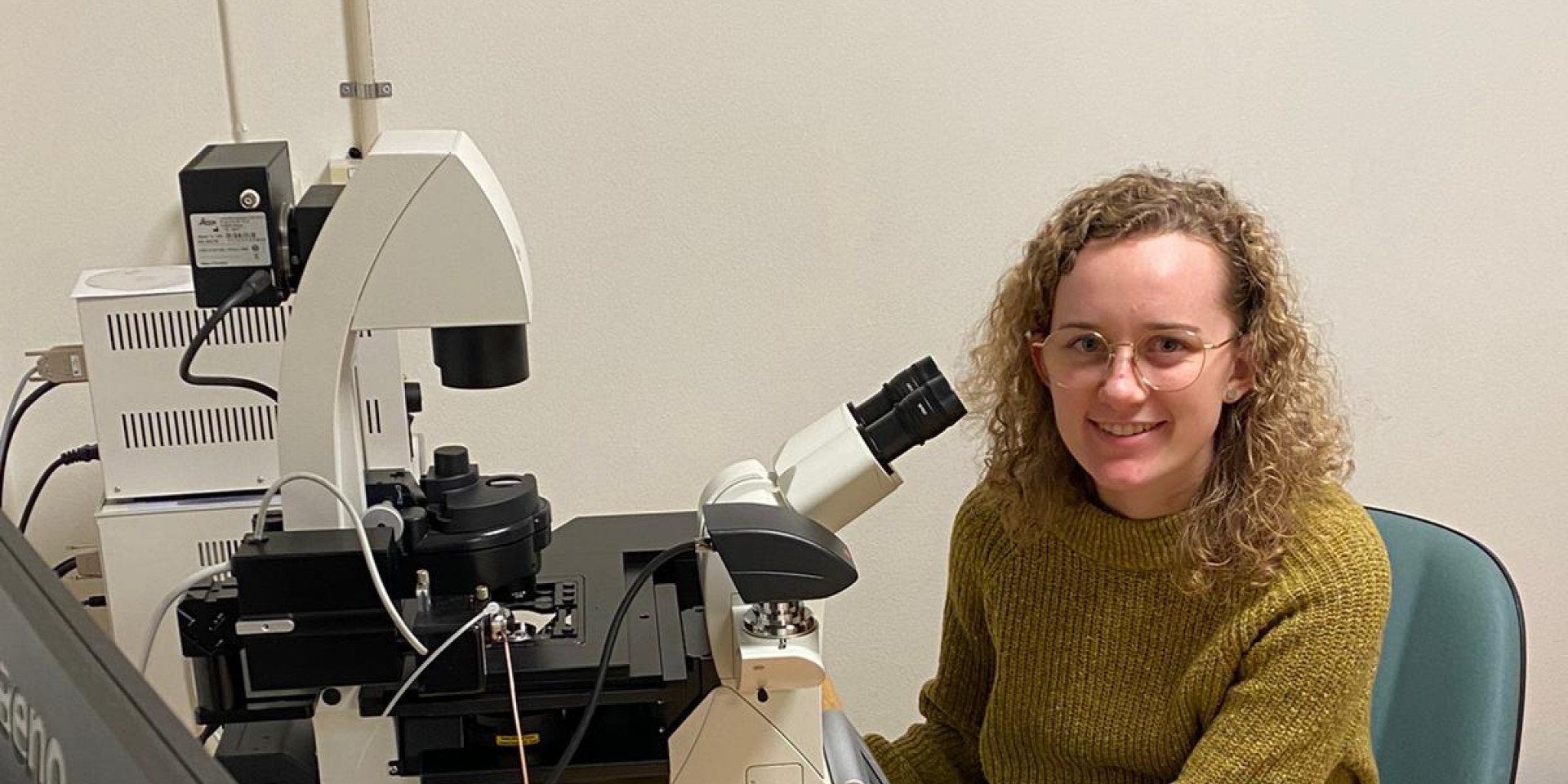 Junge Frau sitzt vor Mikroskop