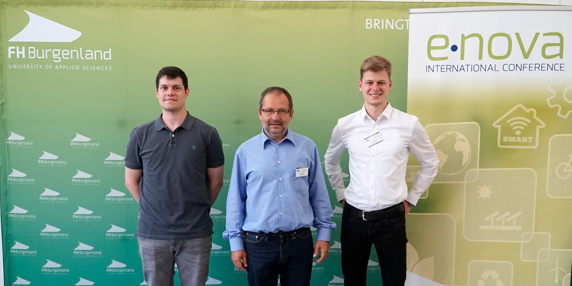 Drei Personen vor Banner e-nova Kongress